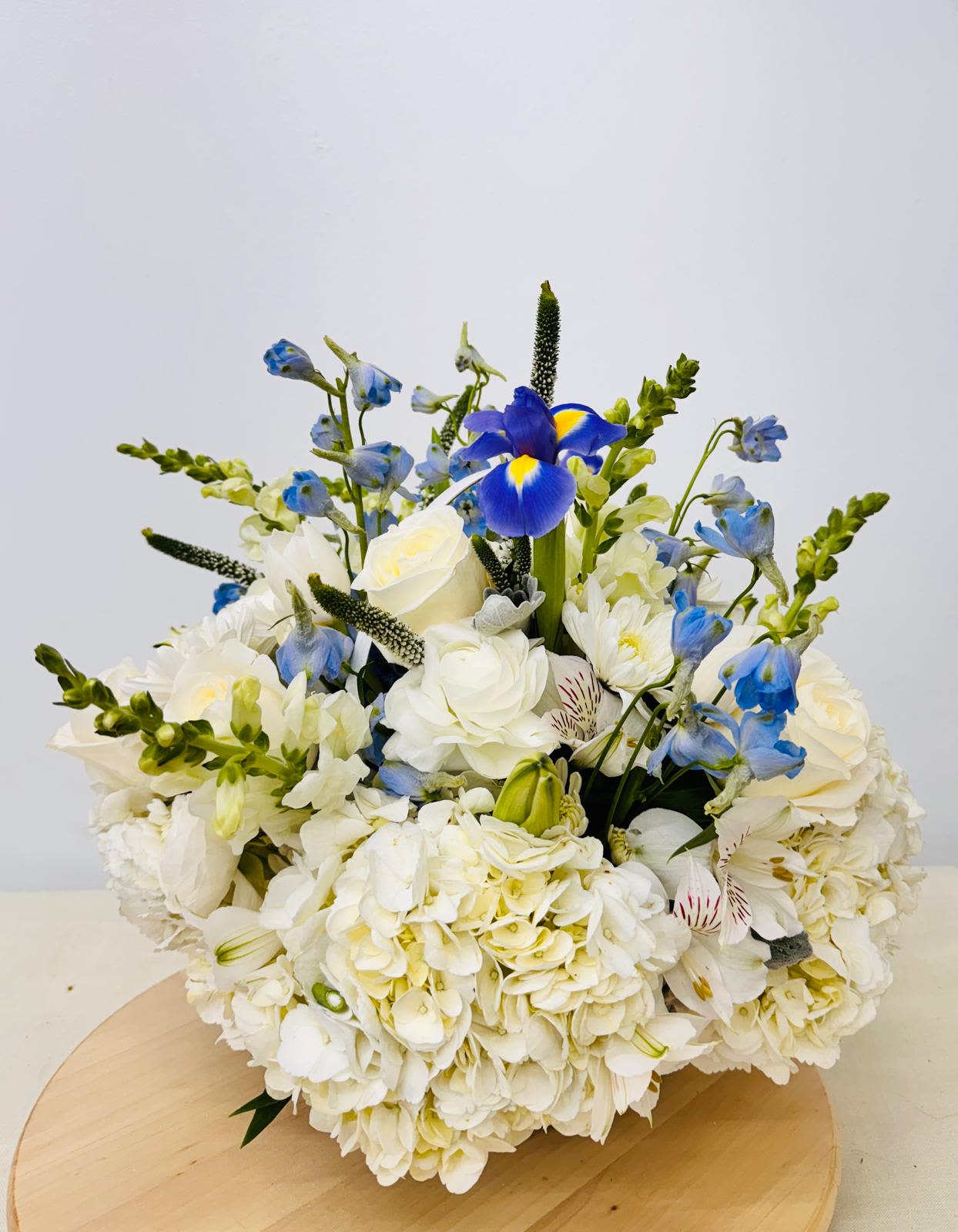 White and blue floral arrangement with roses and iris on a round table