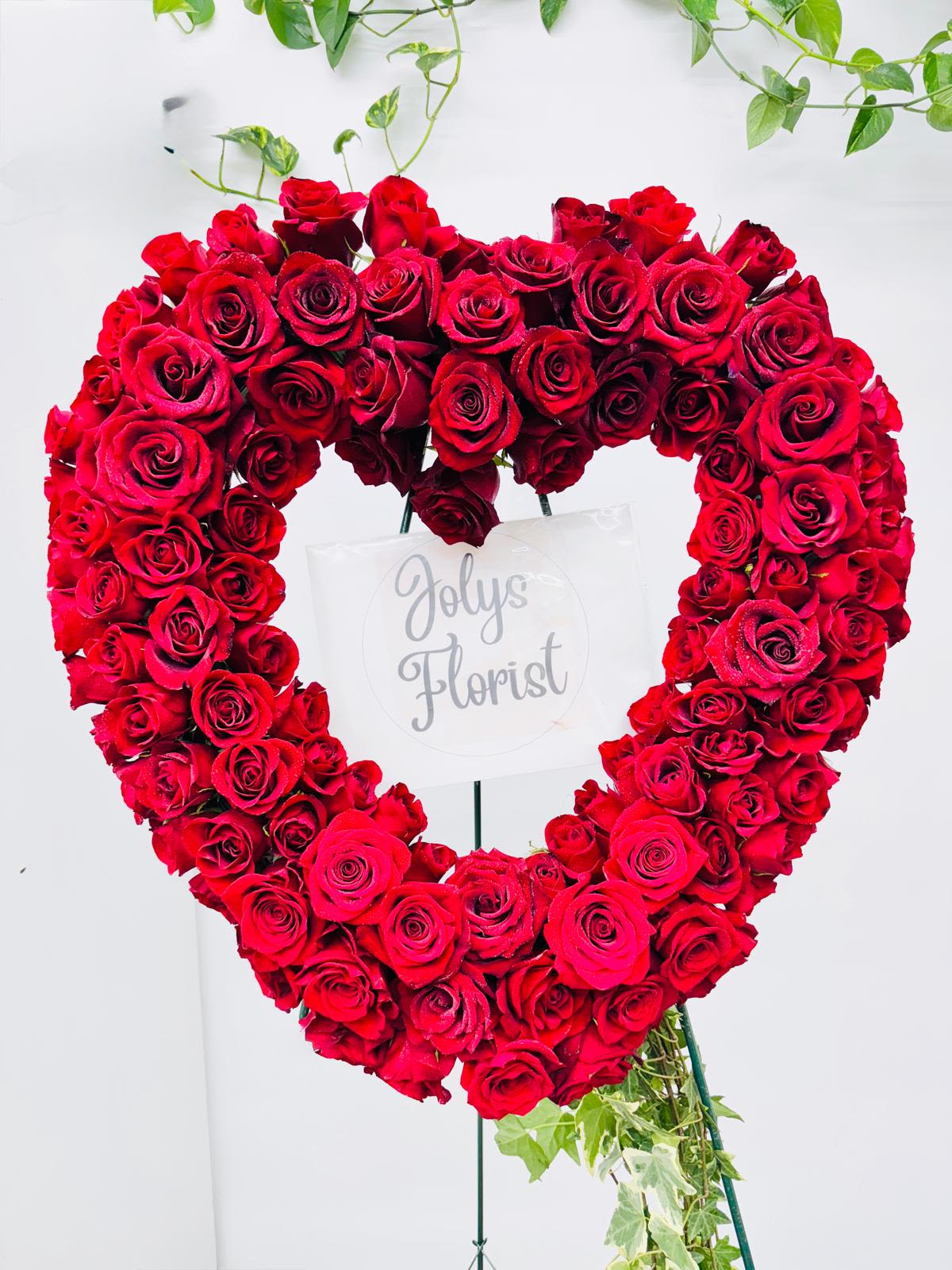 Heart-shaped arrangement of red roses on a stand