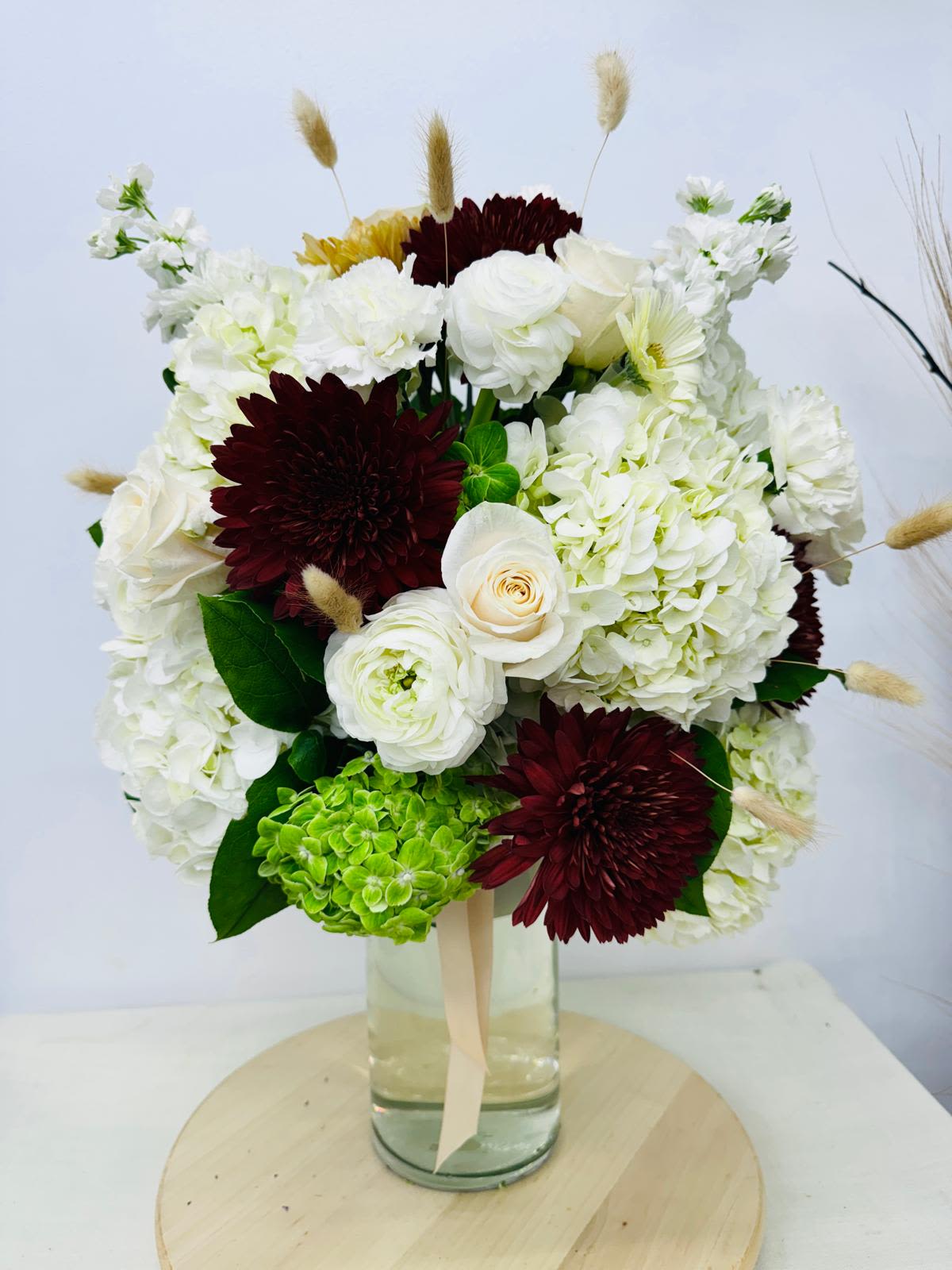 Bouquet of white and burgundy flowers in a glass vase