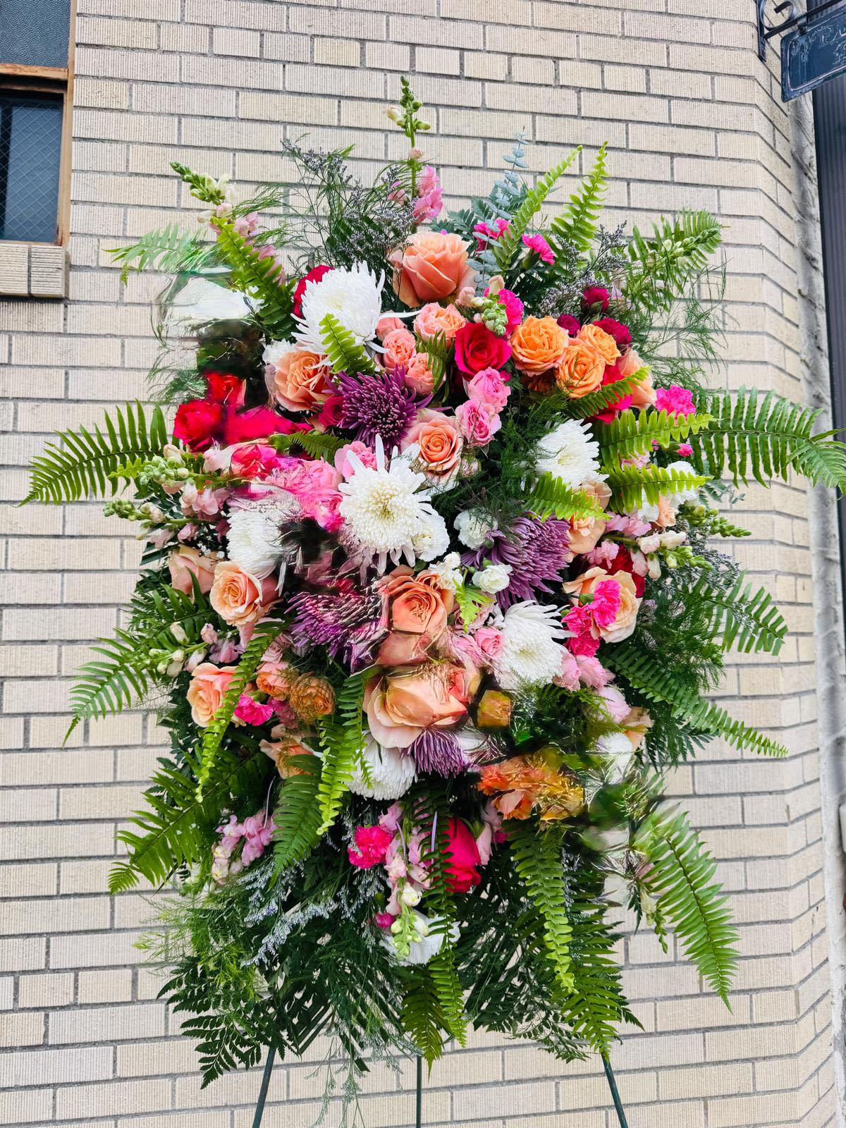 Large standing floral spray with pink, peach, white, and purple flowers