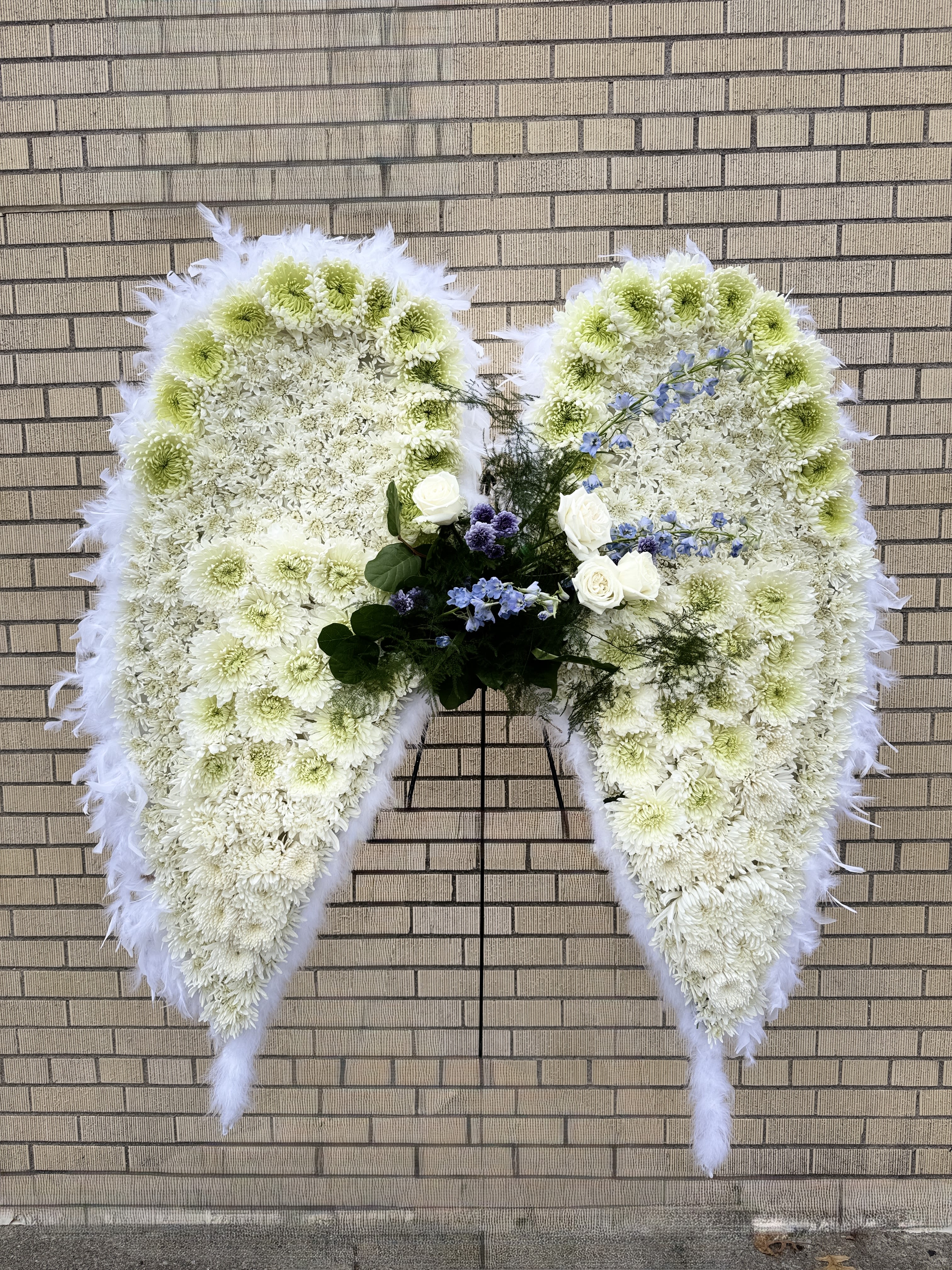 Large white floral funeral wreath shaped like angel wings
