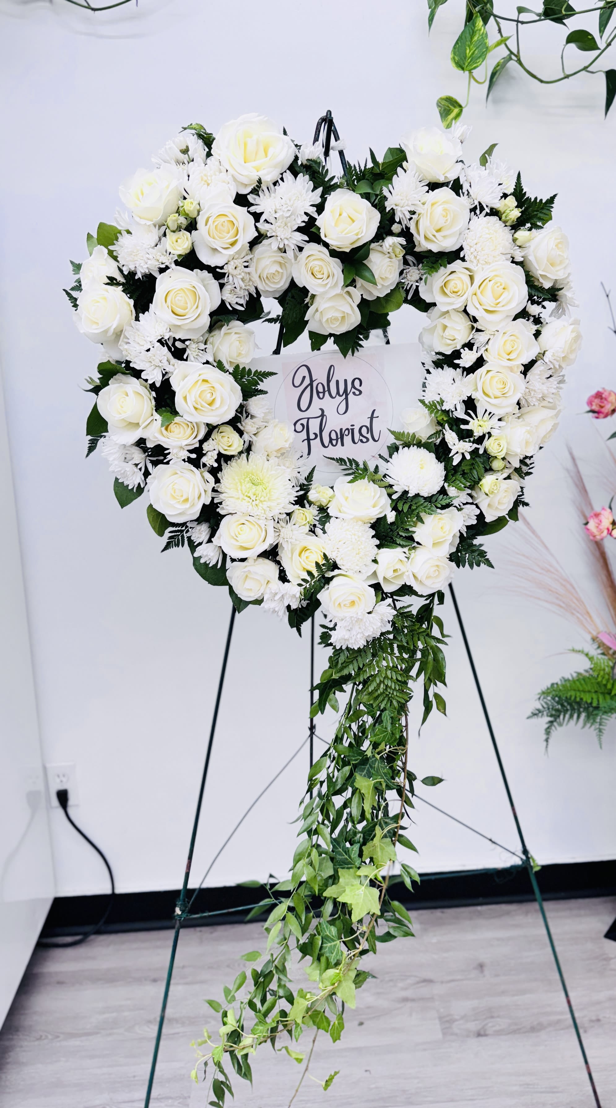 Our Memories (22") - An all white tribute, this heart shaped easel shows your everlasting love. Featuring a variety of white flowers and greenery, this heart with a trail of ivy compliments the beauty of life. 