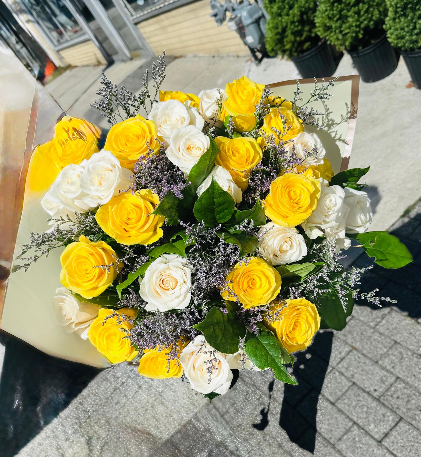 Bouquet of yellow and white roses with purple filler flowers