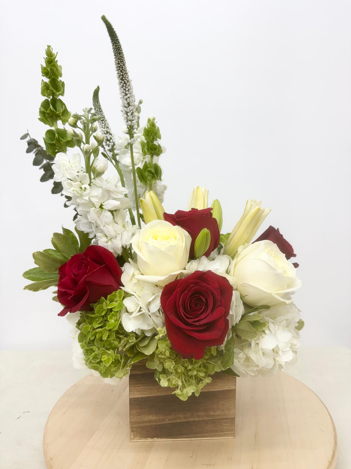 Red and white roses with white hydrangeas in a wooden box