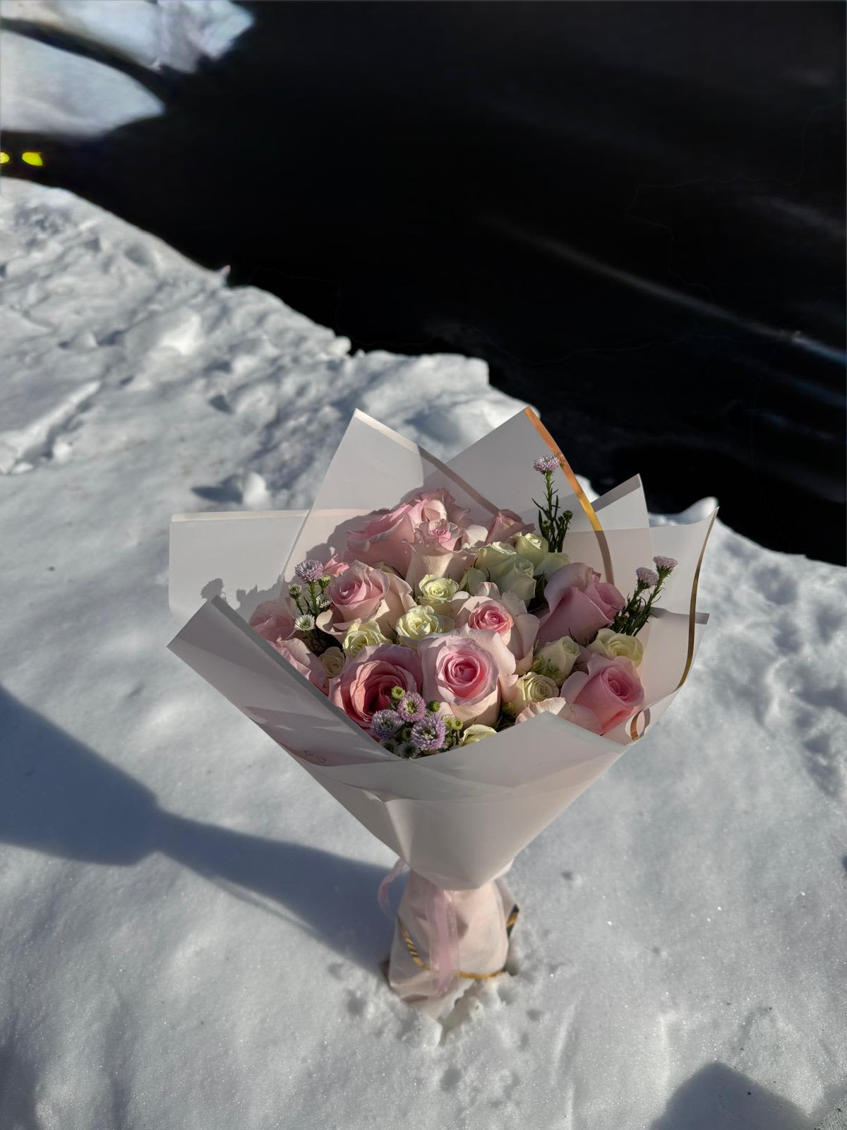 Bouquet of pink and white roses wrapped in white paper