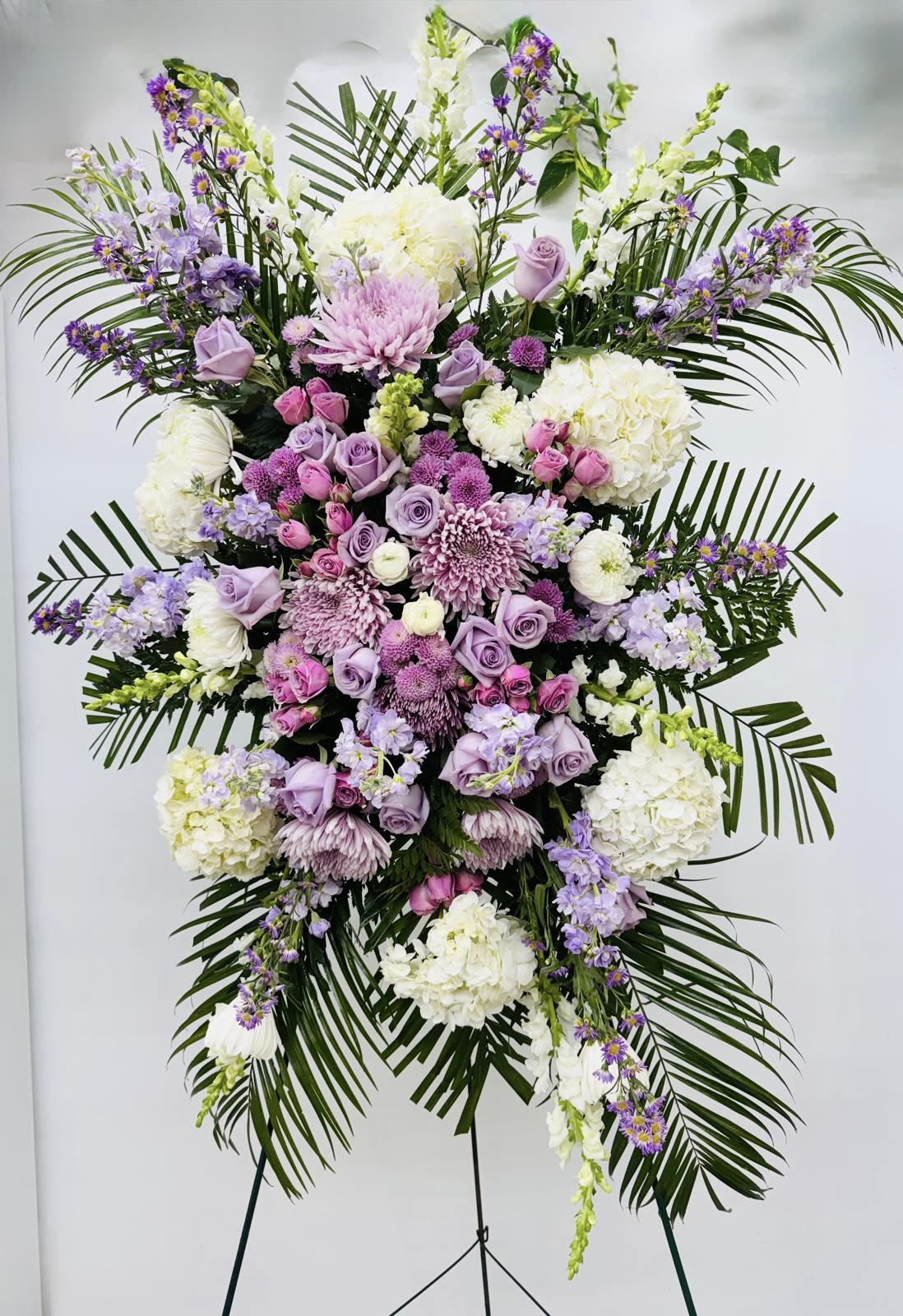 Large standing floral spray in lavender, pink, and white on a stand