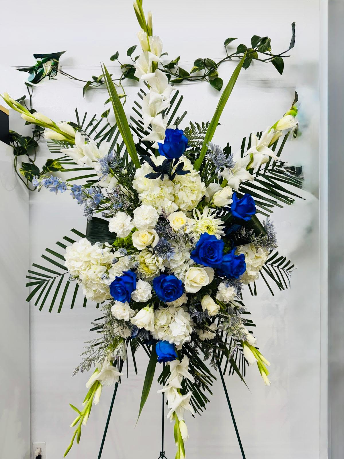 Large standing floral spray with white and blue flowers on an easel