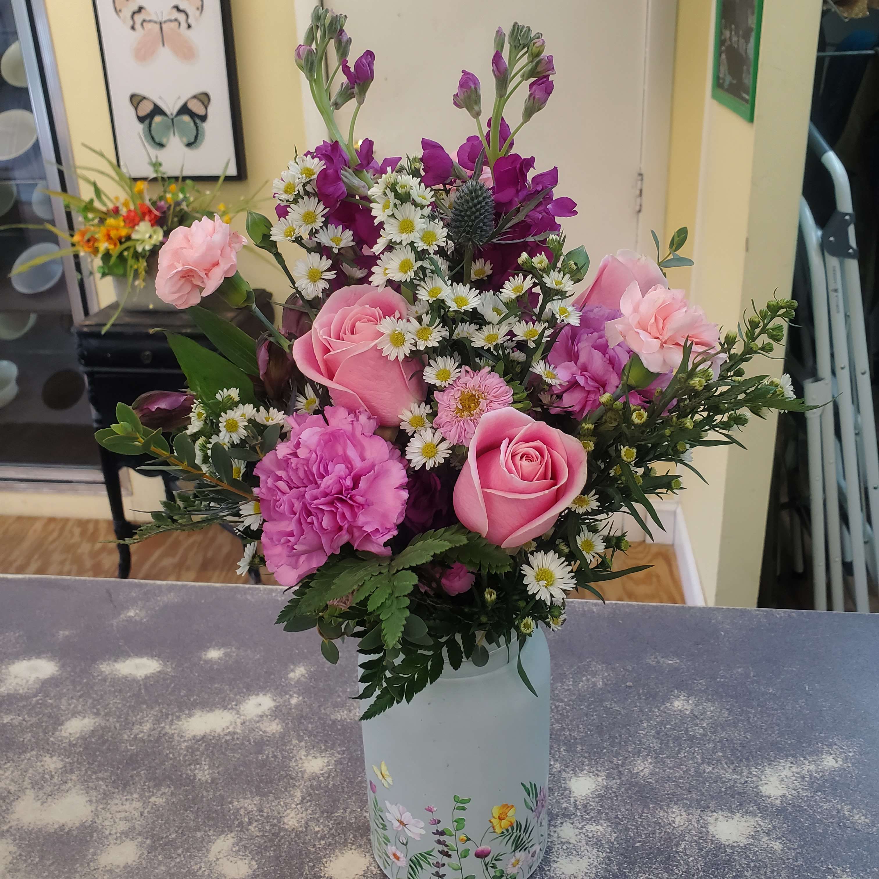 Pink roses and mixed purple flowers in a decorated vase