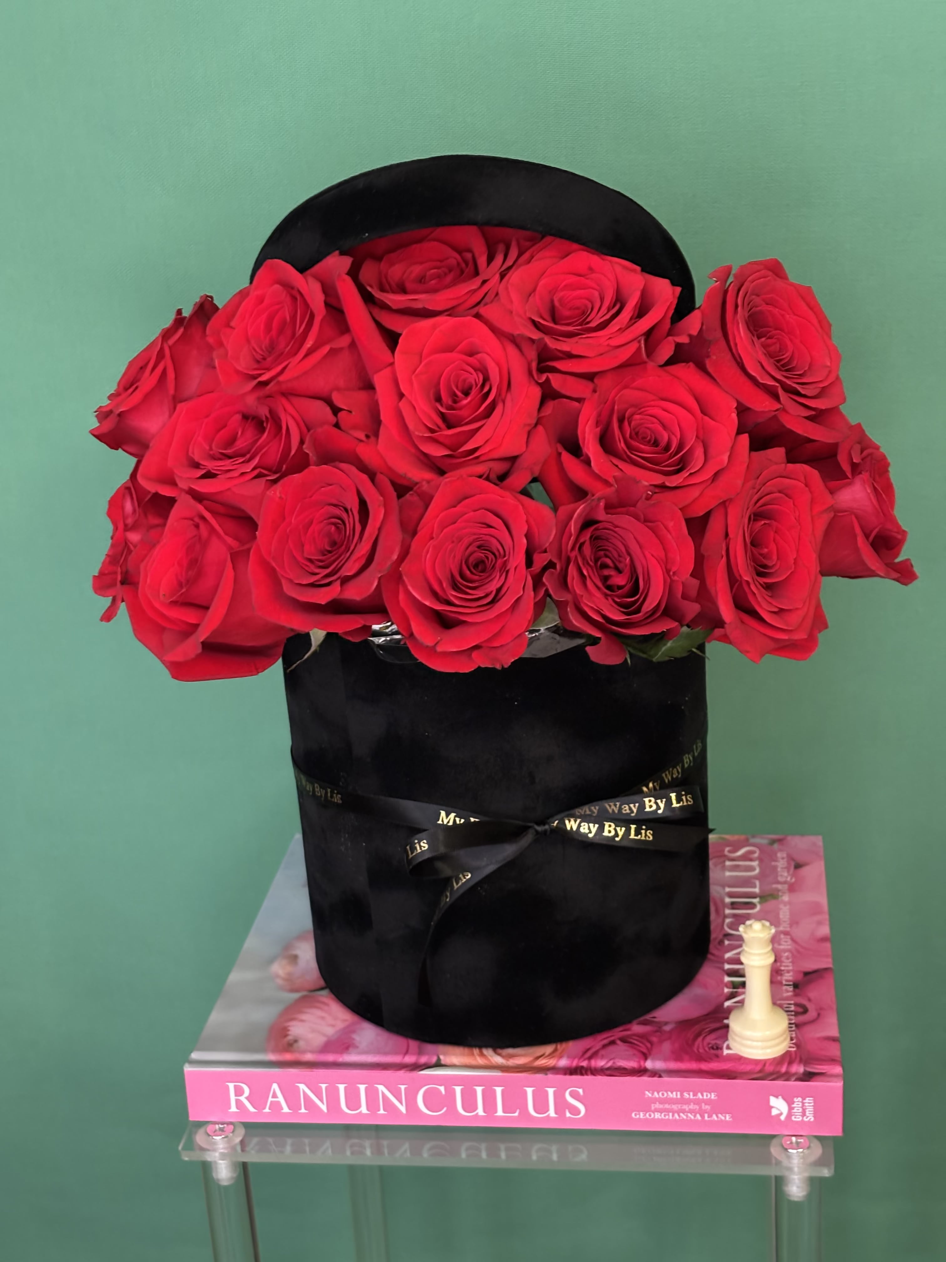 Red roses arranged in a black hatbox with a ribbon