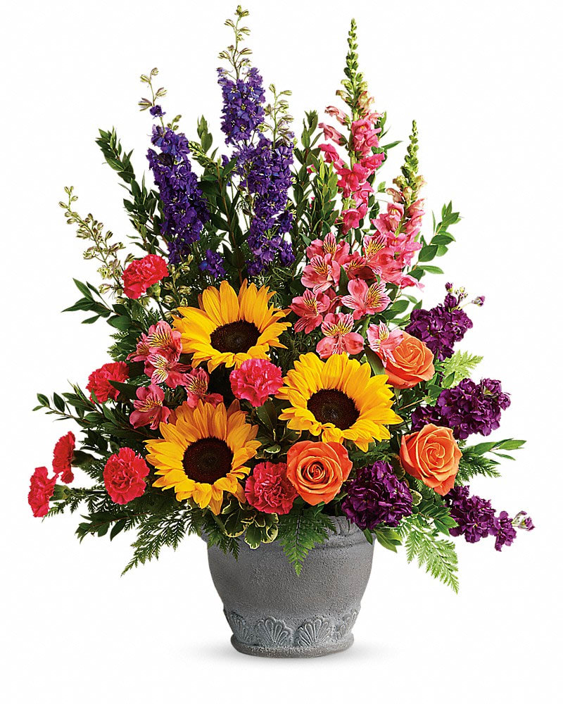 Mixed bouquet in a gray vase with sunflowers, roses, and purple spikes