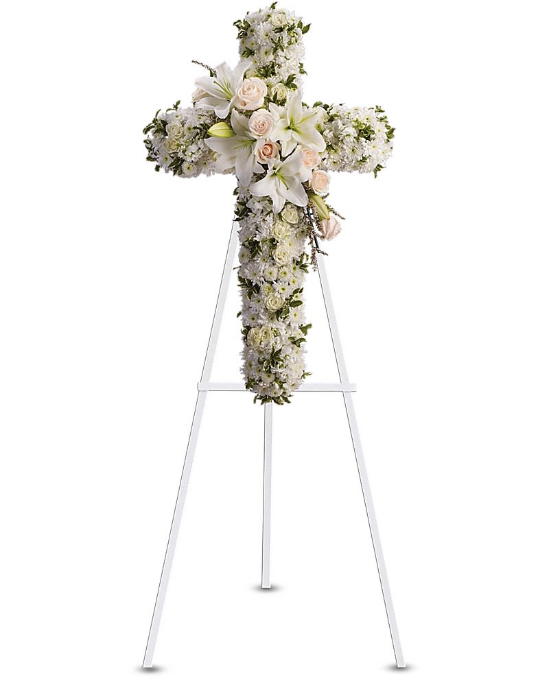 White floral cross arrangement on a stand with lilies and roses