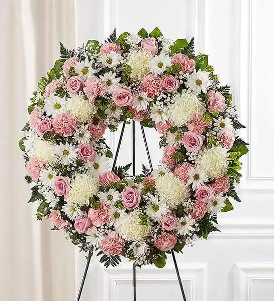 Serene Blessings Standing Wreath- Pink &amp; White   - The memories shared with a loved one can help bring serenity after they are gone. Our standing wreath in pink is a lovely way to celebrate those moments. Expertly crafted by our local florists with graceful pink and white blooms for a lush, full presentation, this traditional funeral arrangement is a beautiful way to honor their life.