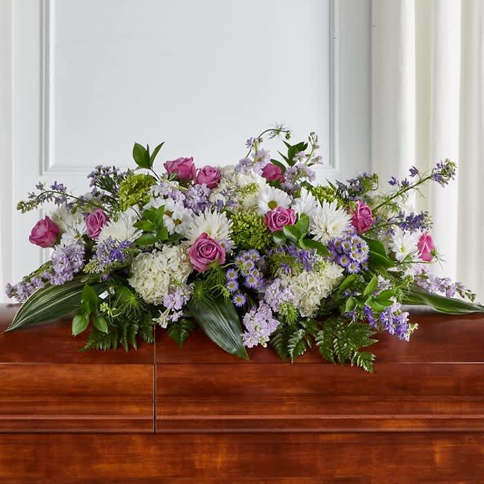 Tender Embrace Casket Spray - When we lose someone dear to us, we want to respond with a fitting gesture of respect and admiration.Half casket cover arrangement of roses, hybrid lilies and monte casino, lavender cremones, spider mums and stock, purple waxflower and fresh greenery Hydrangea etc              Stock  