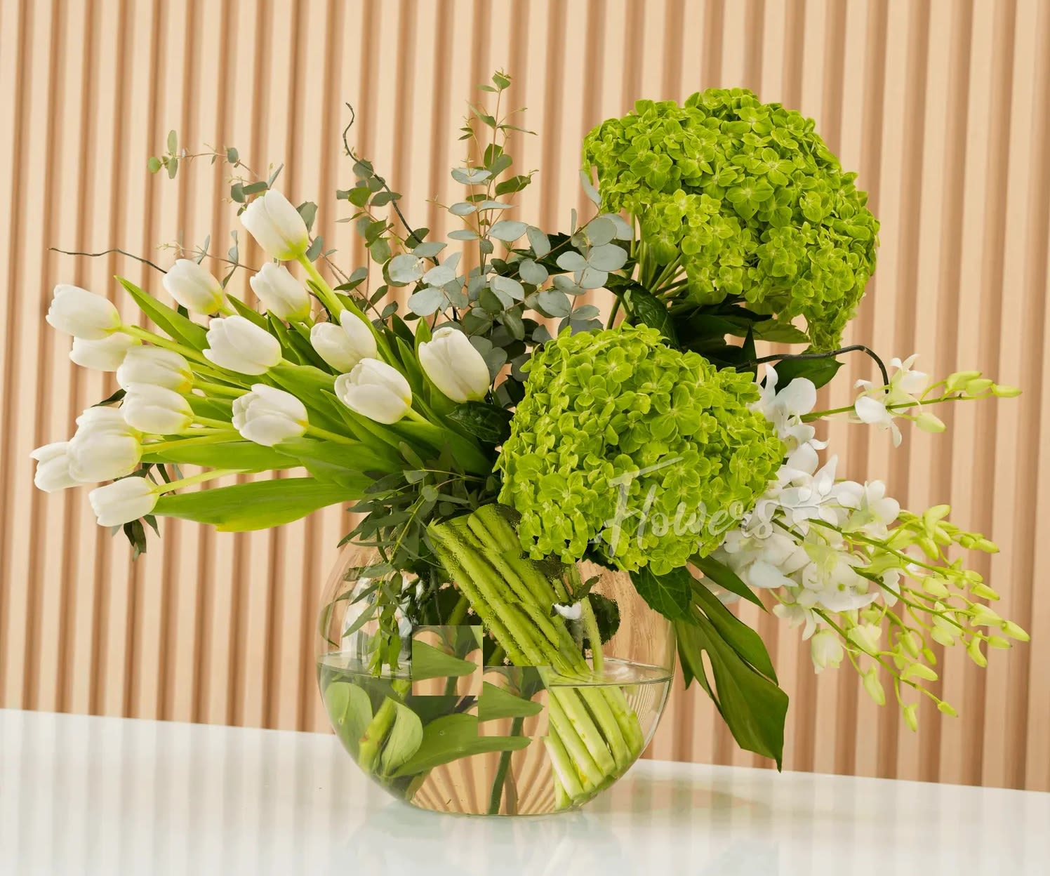 White tulips and green hydrangeas in a clear glass bowl vase