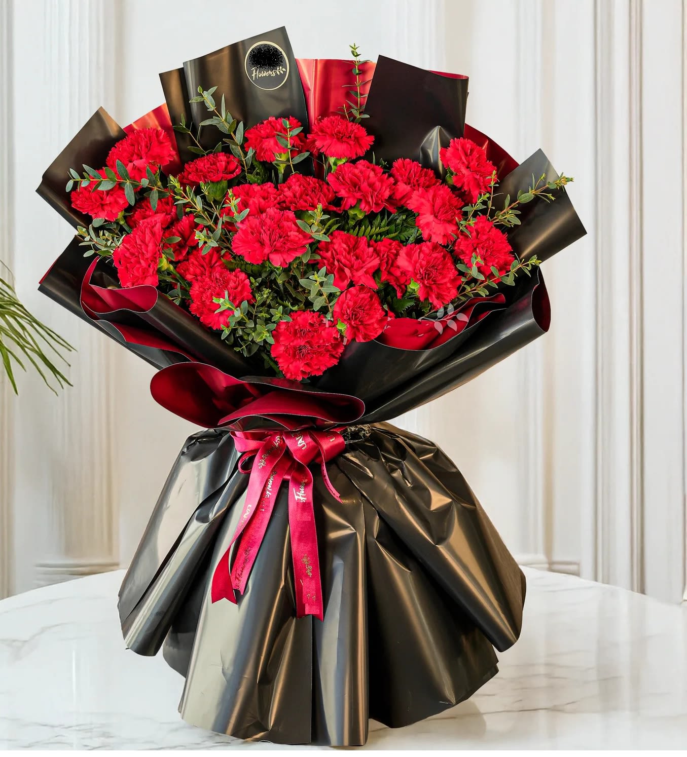 Bouquet of red carnations wrapped in black paper with a red ribbon