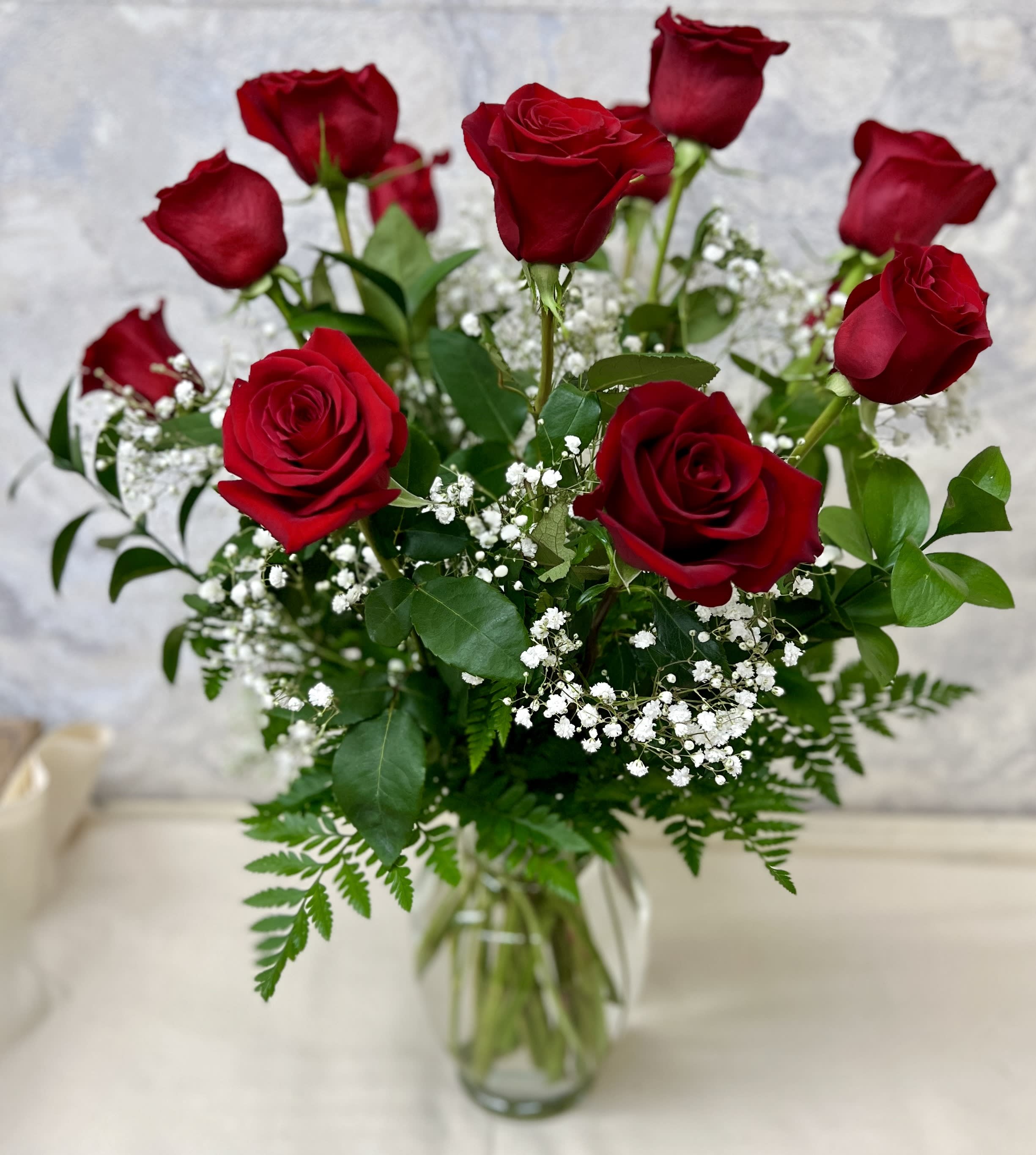 Arrangement of red roses with white filler flowers in a clear glass vase