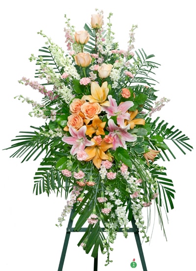 Tall standing floral spray with peach roses, lilies, and pink accents on an easel