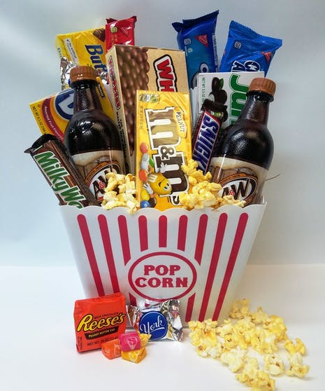 Popcorn bucket filled with candy bars and two soda bottles