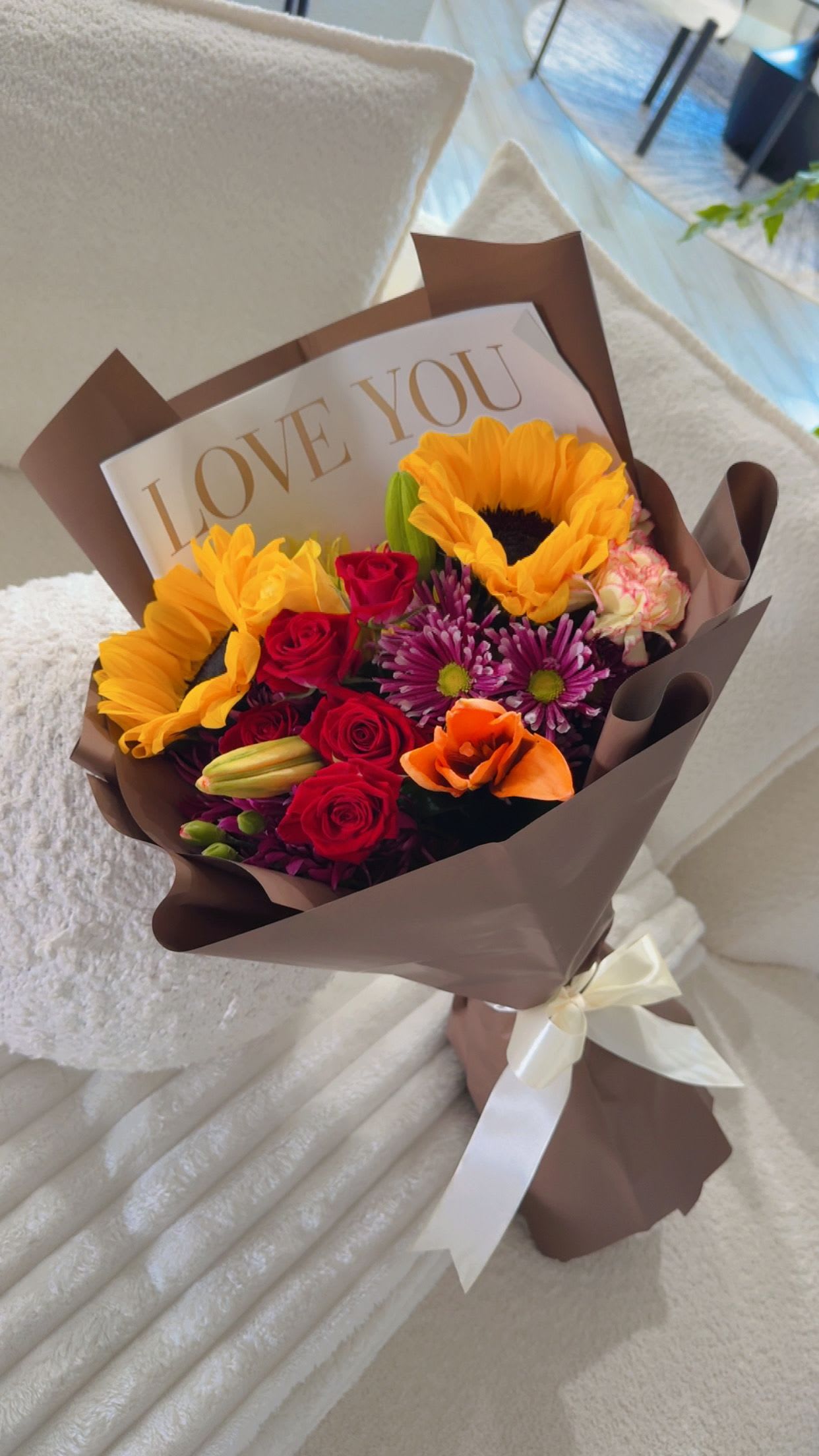 Golden Love Bouquet  - A vibrant mix of sunflowers, roses, and seasonal blooms wrapped in elegant chocolate tones. Designed to brighten their day with warmth, love, and bold beauty. 