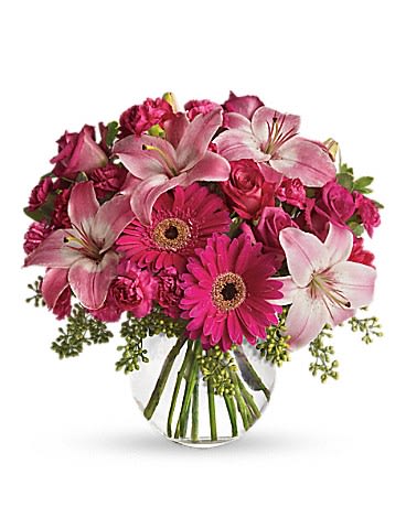 Pink lilies, roses, and gerbera daisies in a clear glass vase