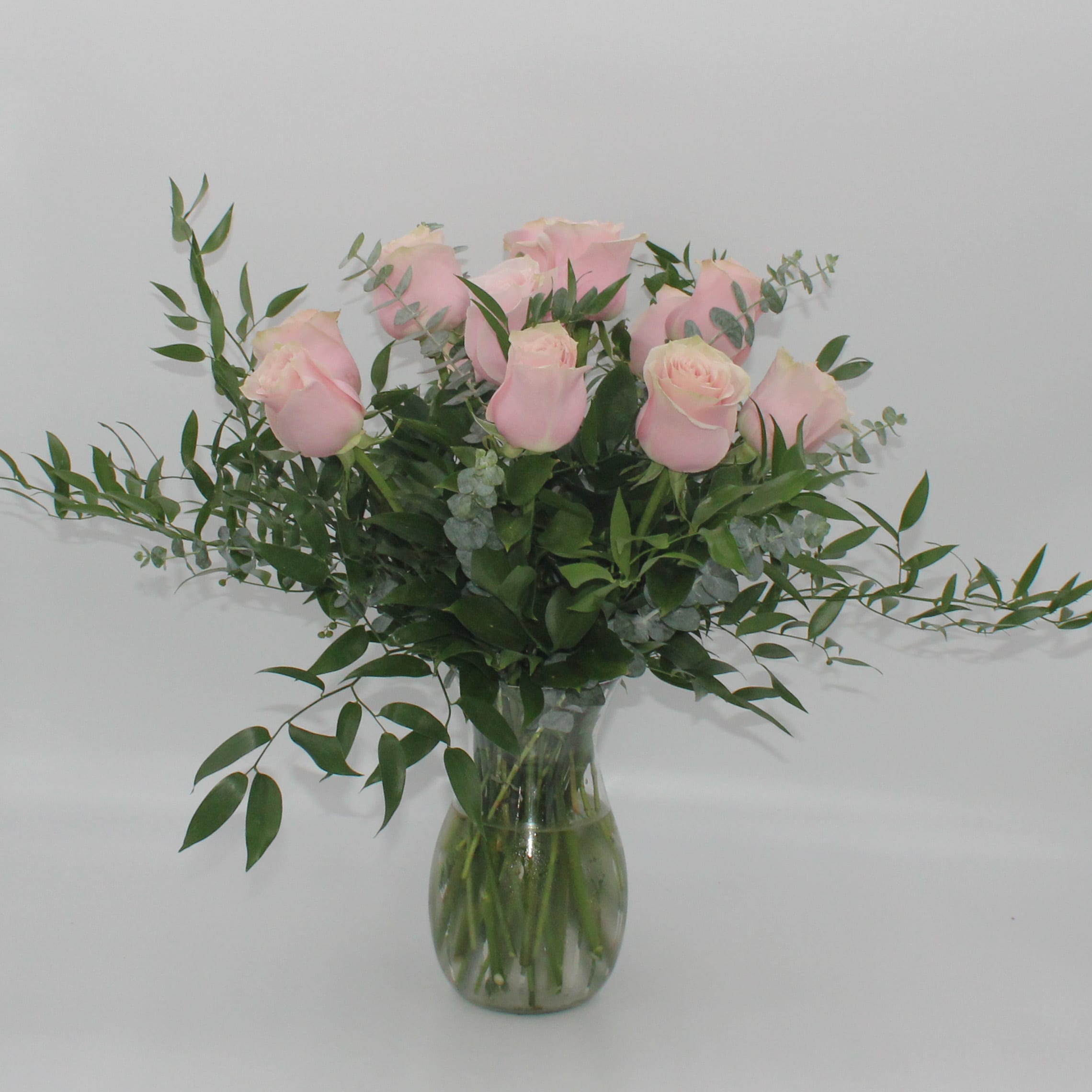 Pink roses in a clear glass vase with airy greenery