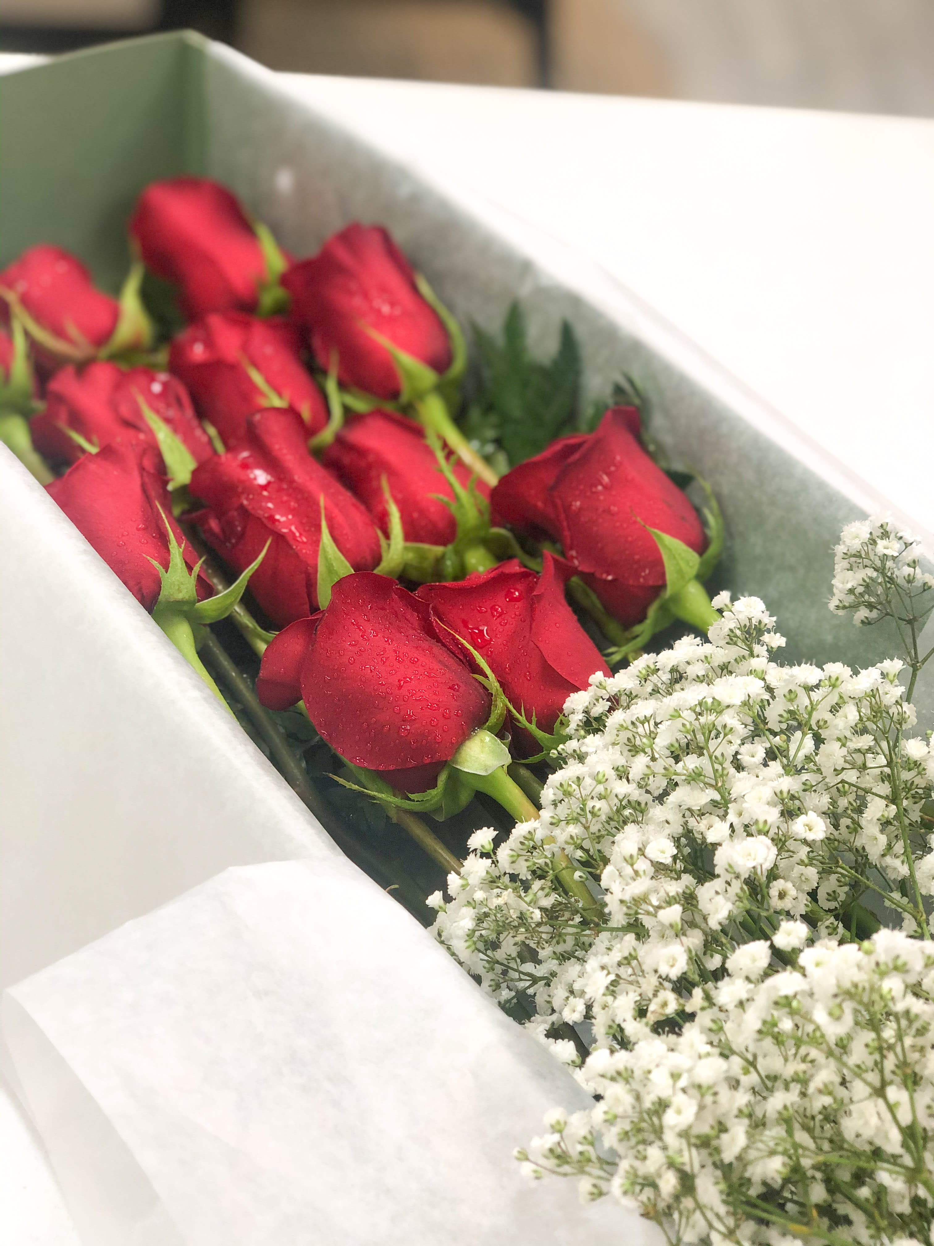 Red roses with white baby's breath in a wrapped bouquet