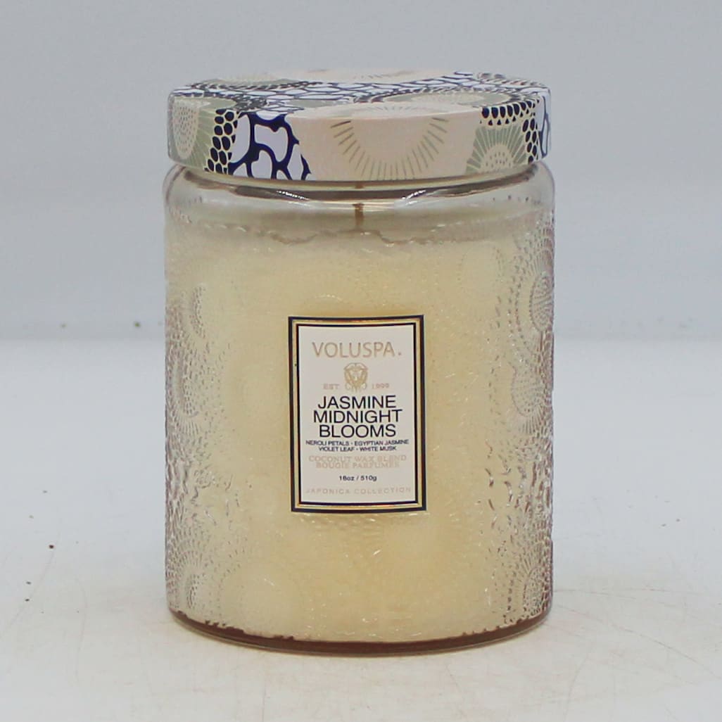 A jasmine-scented candle in a glass jar with a patterned lid