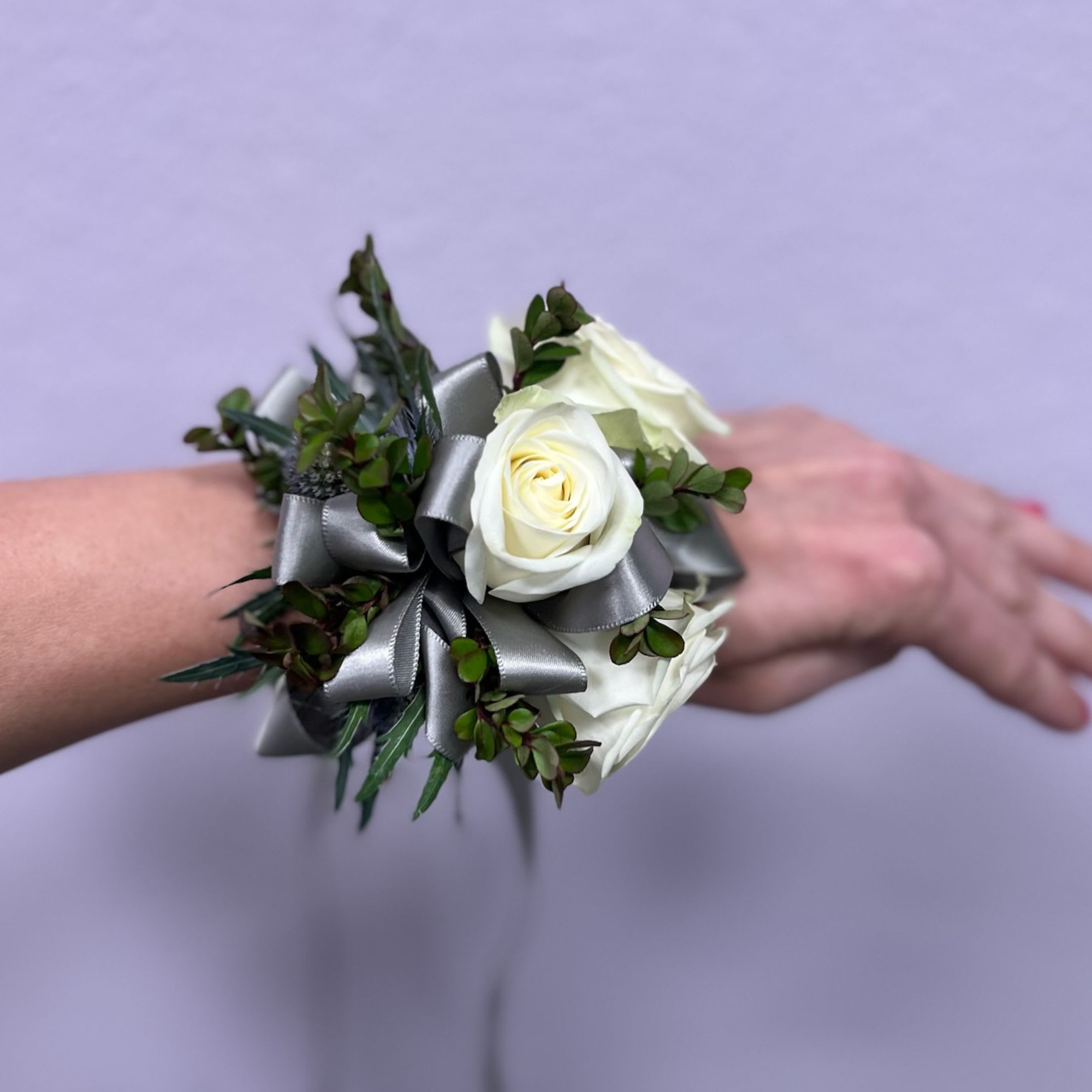 White rose wrist corsage with silver ribbon and greenery