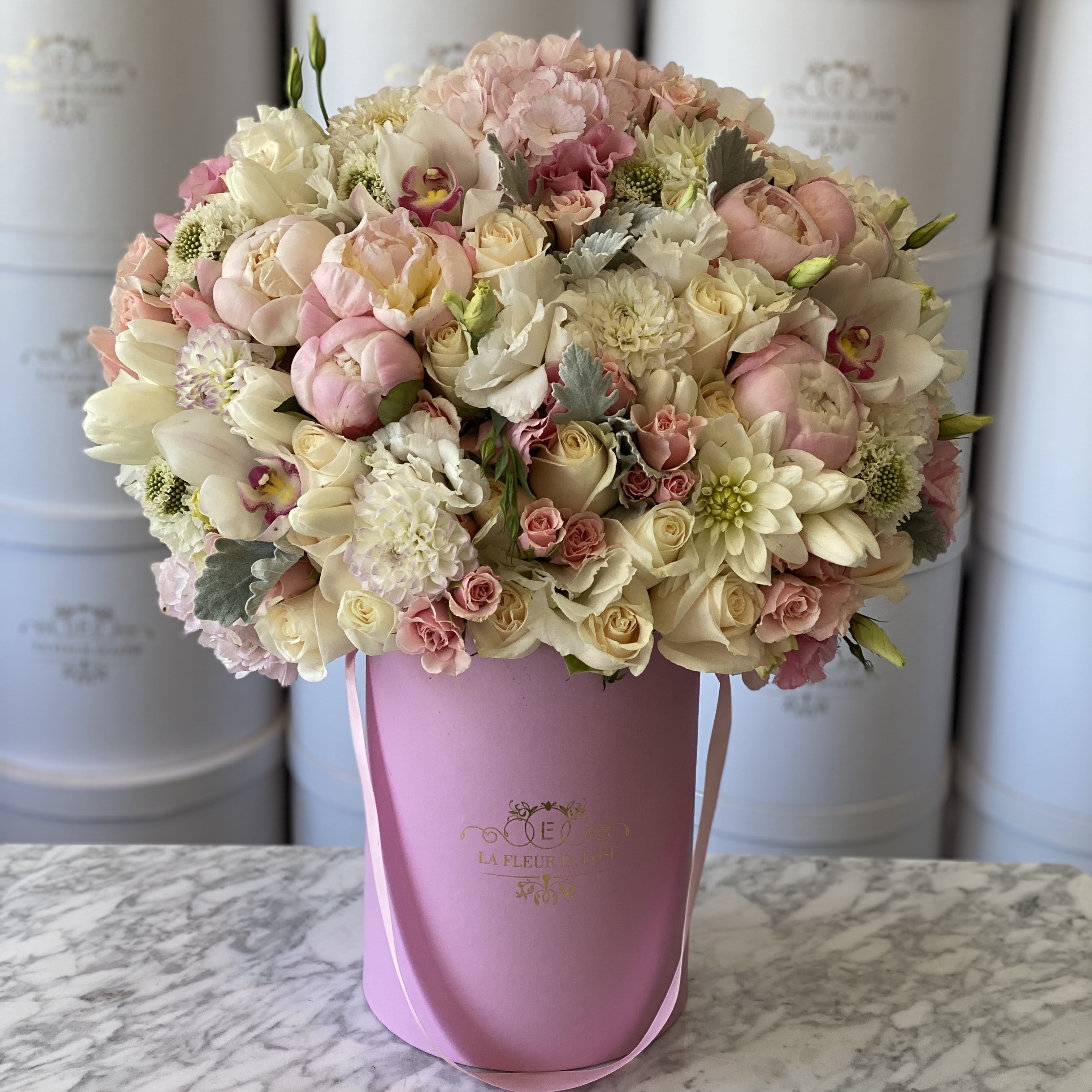 Miss Pinks  - Fashionable pinks and whites with peonies and dusty miller in our signature pink small box. Premium is available in the same color pink large box   Seasonal flowers will be substituted 
