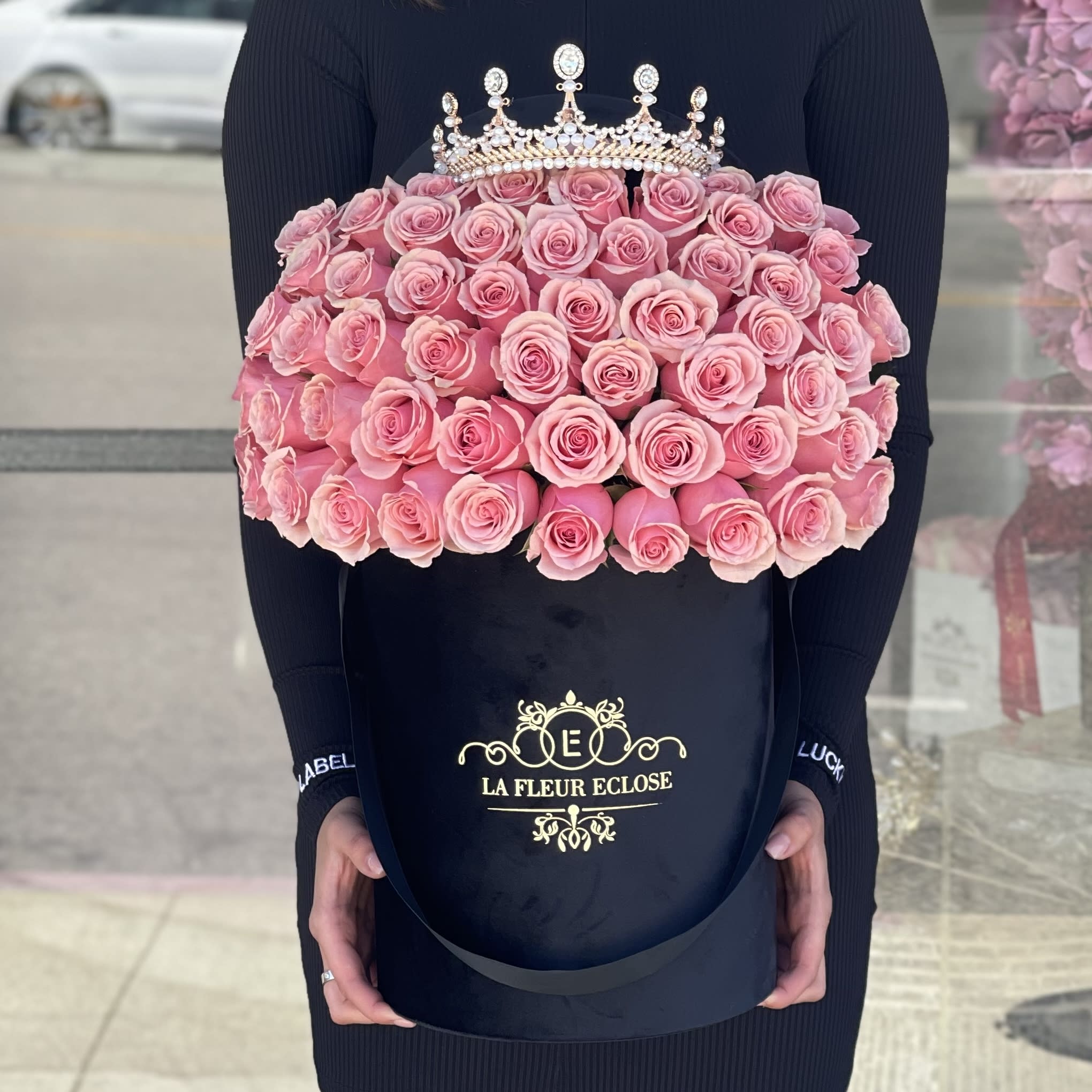 Large bouquet of pink roses in a black hatbox with a jeweled crown topper