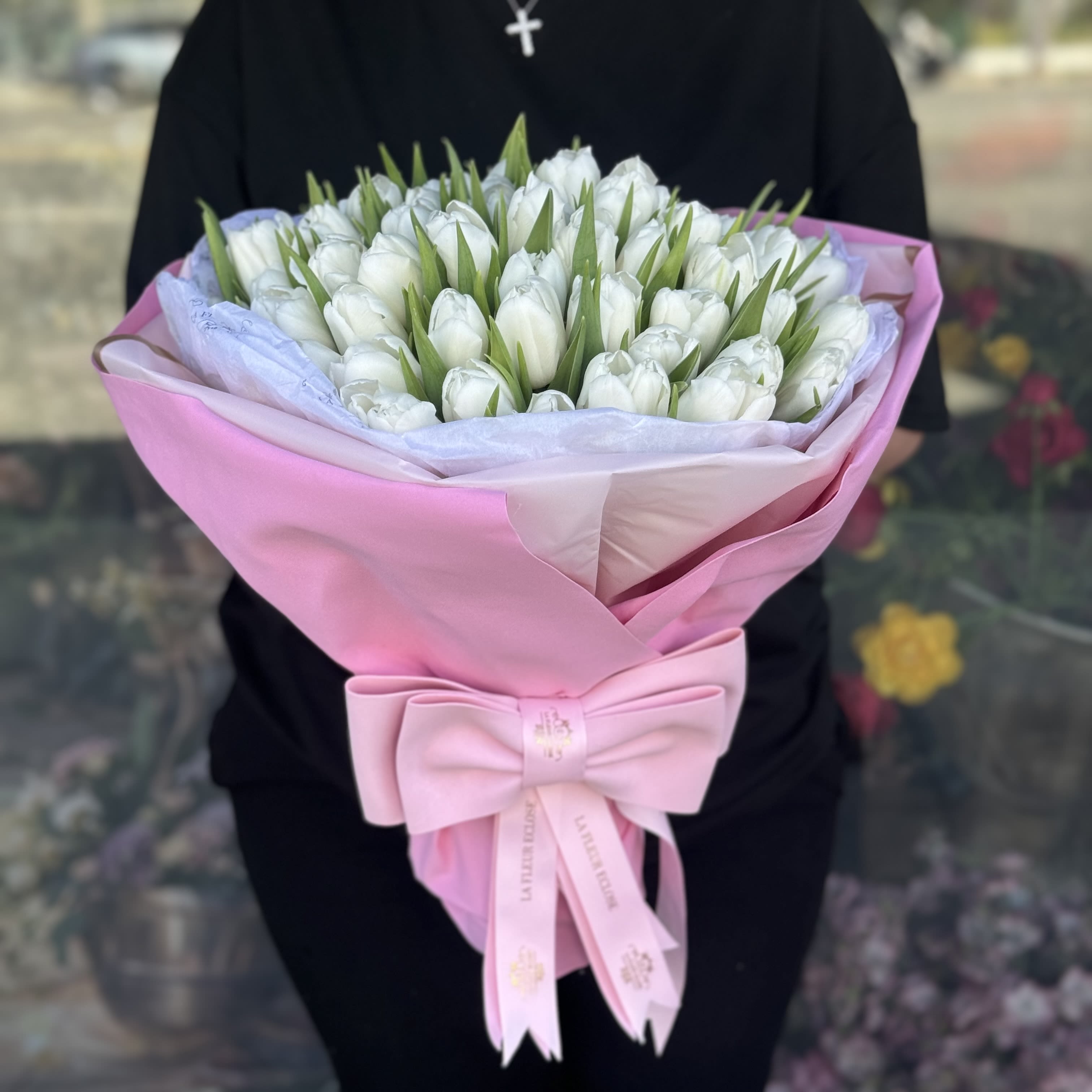 Bouquet of white tulips wrapped in pink paper with a bow