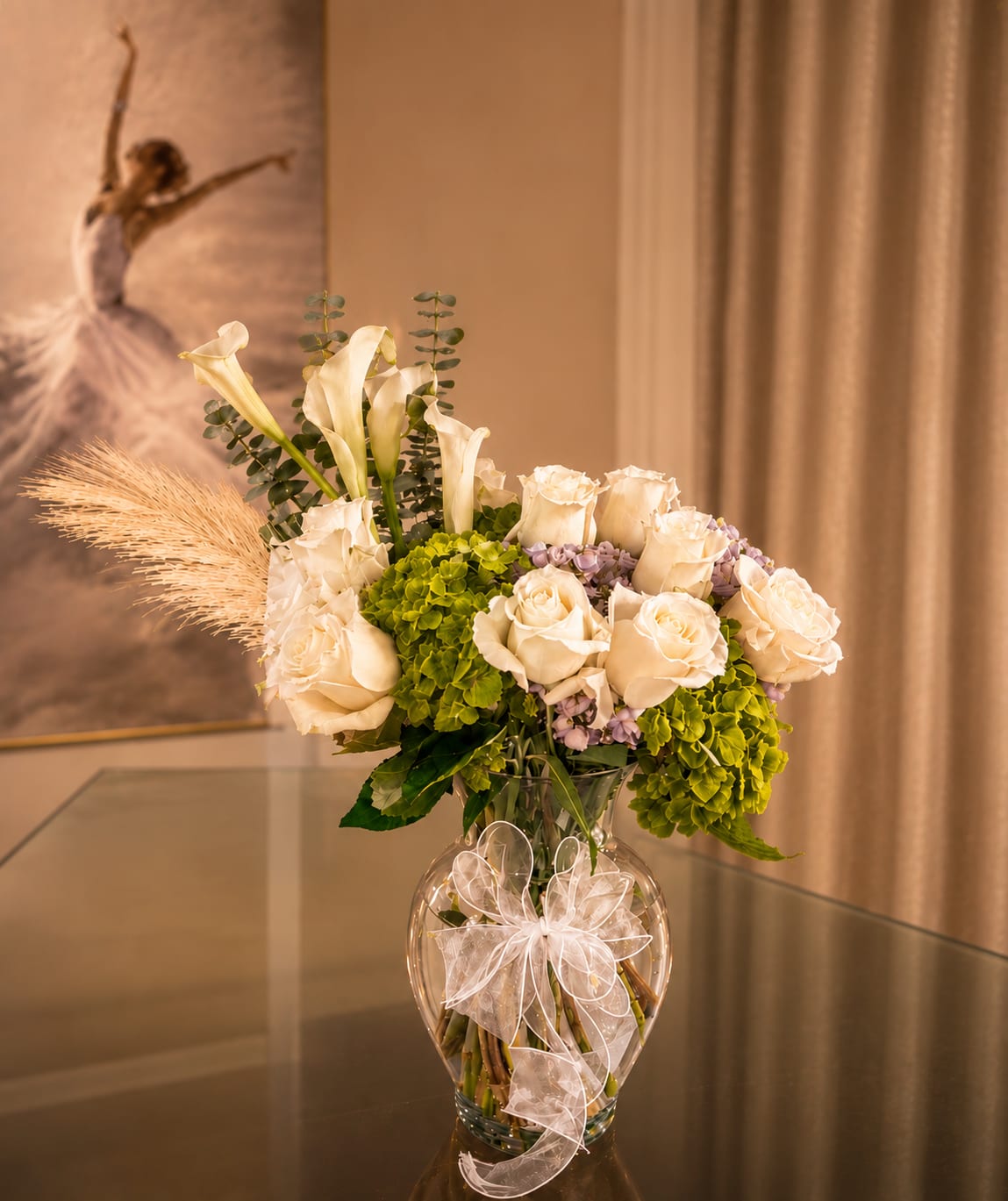 Romance - A luminous couture-style arrangement where ivory roses bloom like porcelain silk against vibrant green hydrangeas and delicate lavender accents. Elegant white calla lilies rise above the bouquet with sculptural grace, while soft eucalyptus and feathery pampas details create movement and depth. 