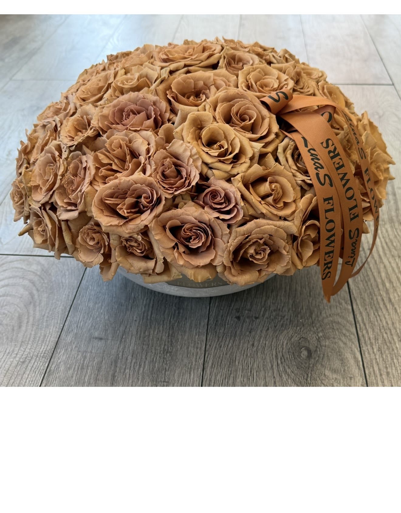 Round bouquet of tan roses with an orange ribbon
