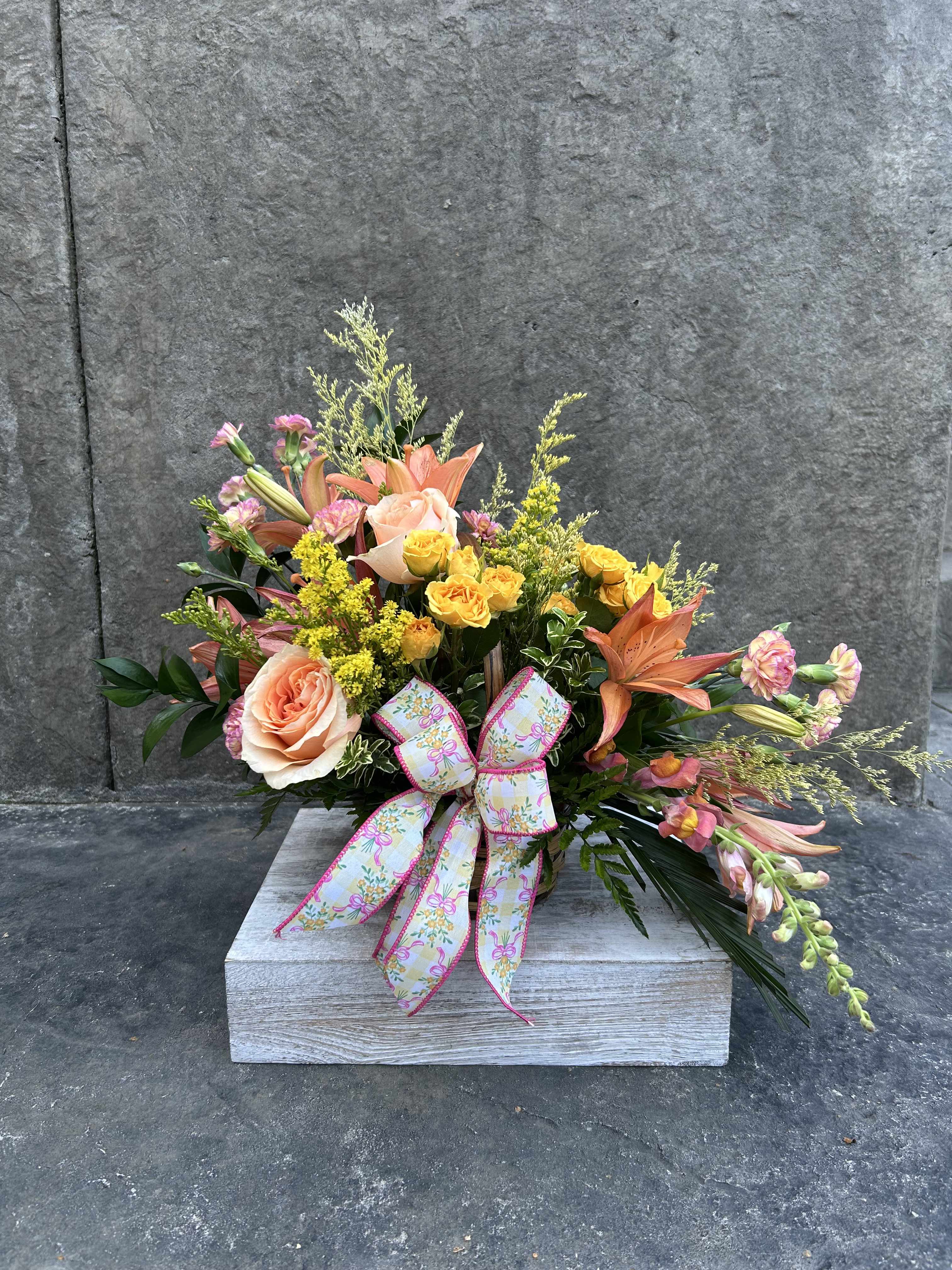 Mixed bouquet of peach roses, yellow spray roses, and orange lilies in a wooden box