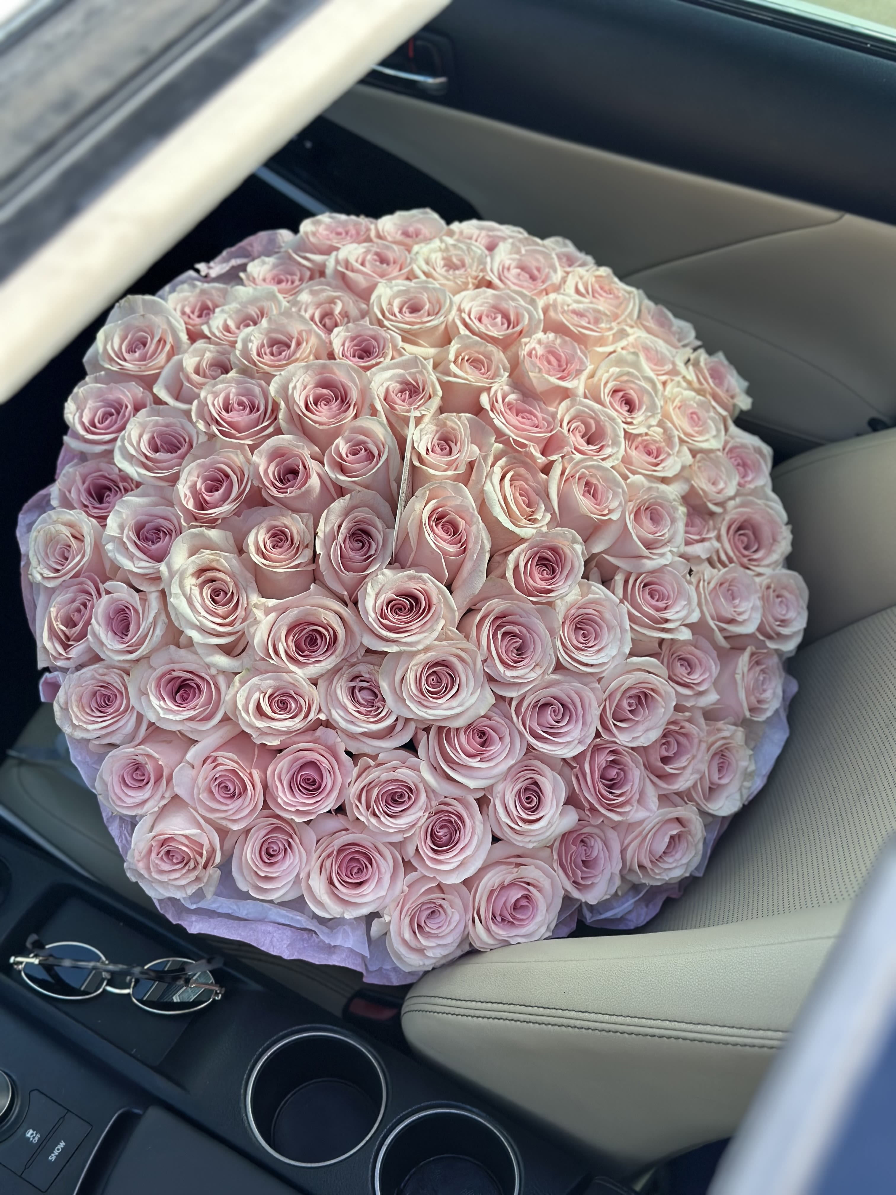 Large round bouquet of pale pink roses on a car seat
