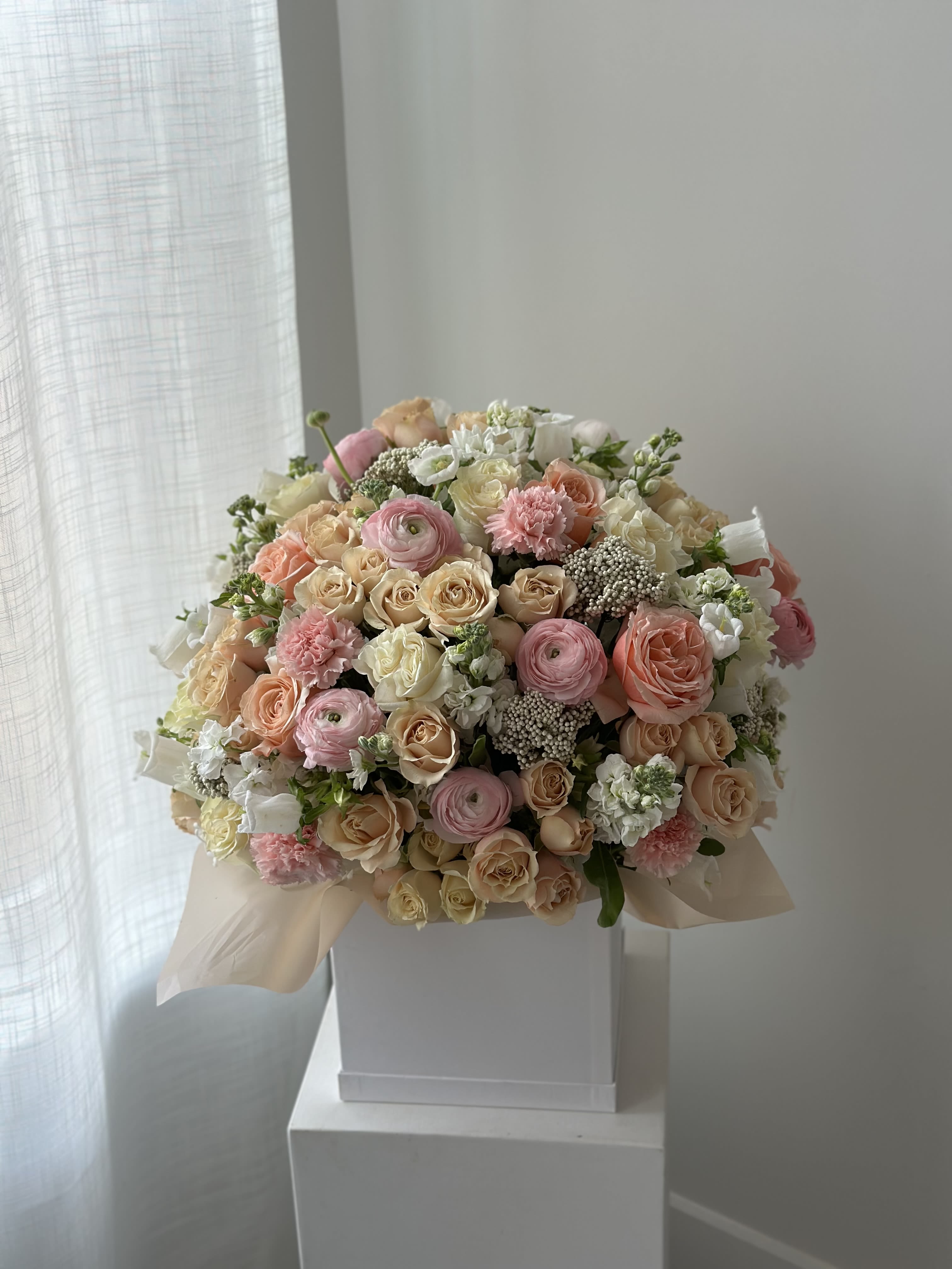 Large pastel bouquet of roses, ranunculus, and carnations in a white box