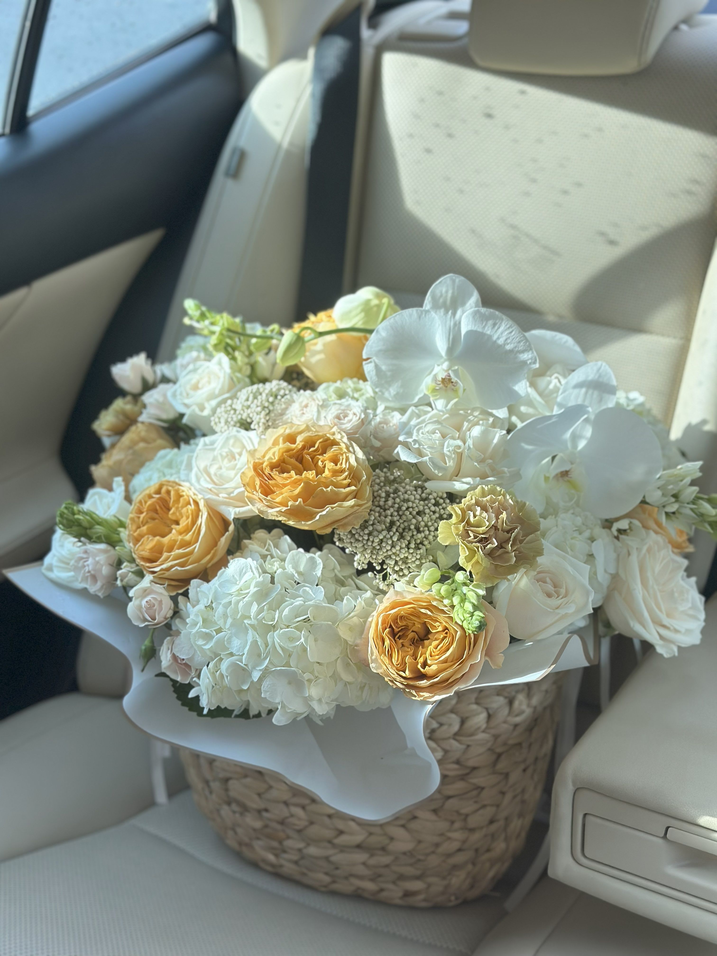 Bouquet of white and peach flowers in a woven basket