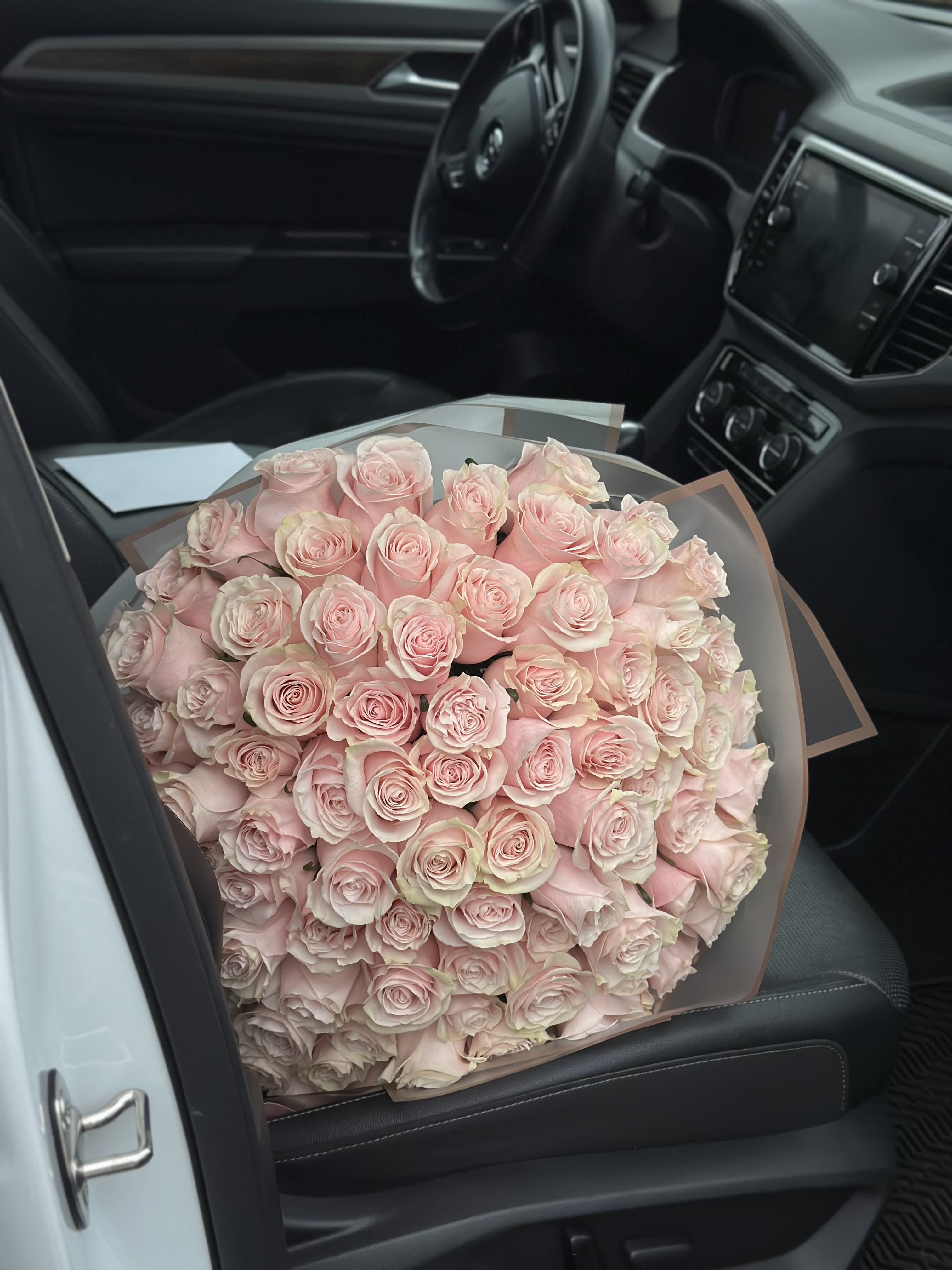 Large bouquet of pale pink roses wrapped in translucent paper