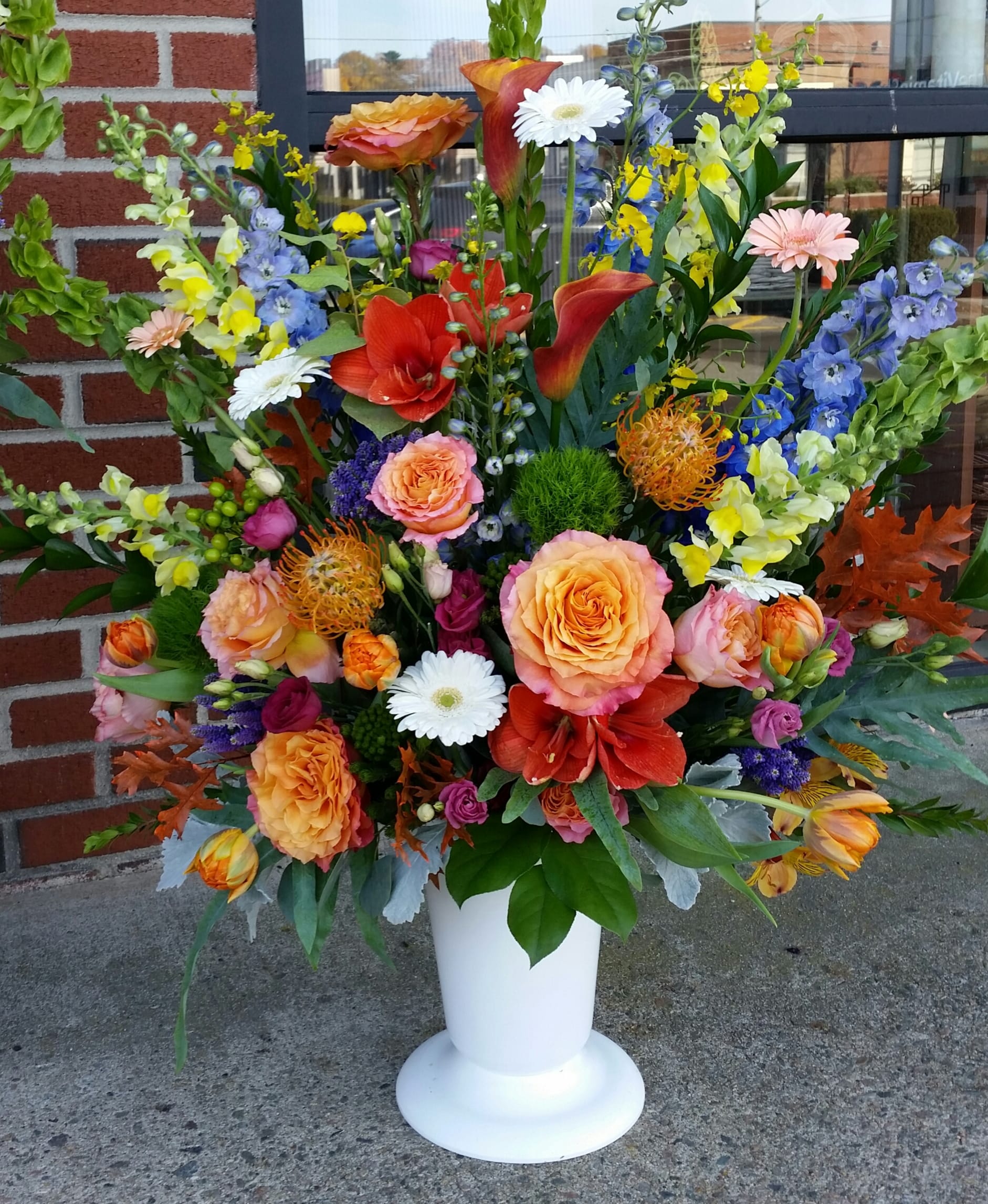 Large mixed flower arrangement in a white pedestal vase