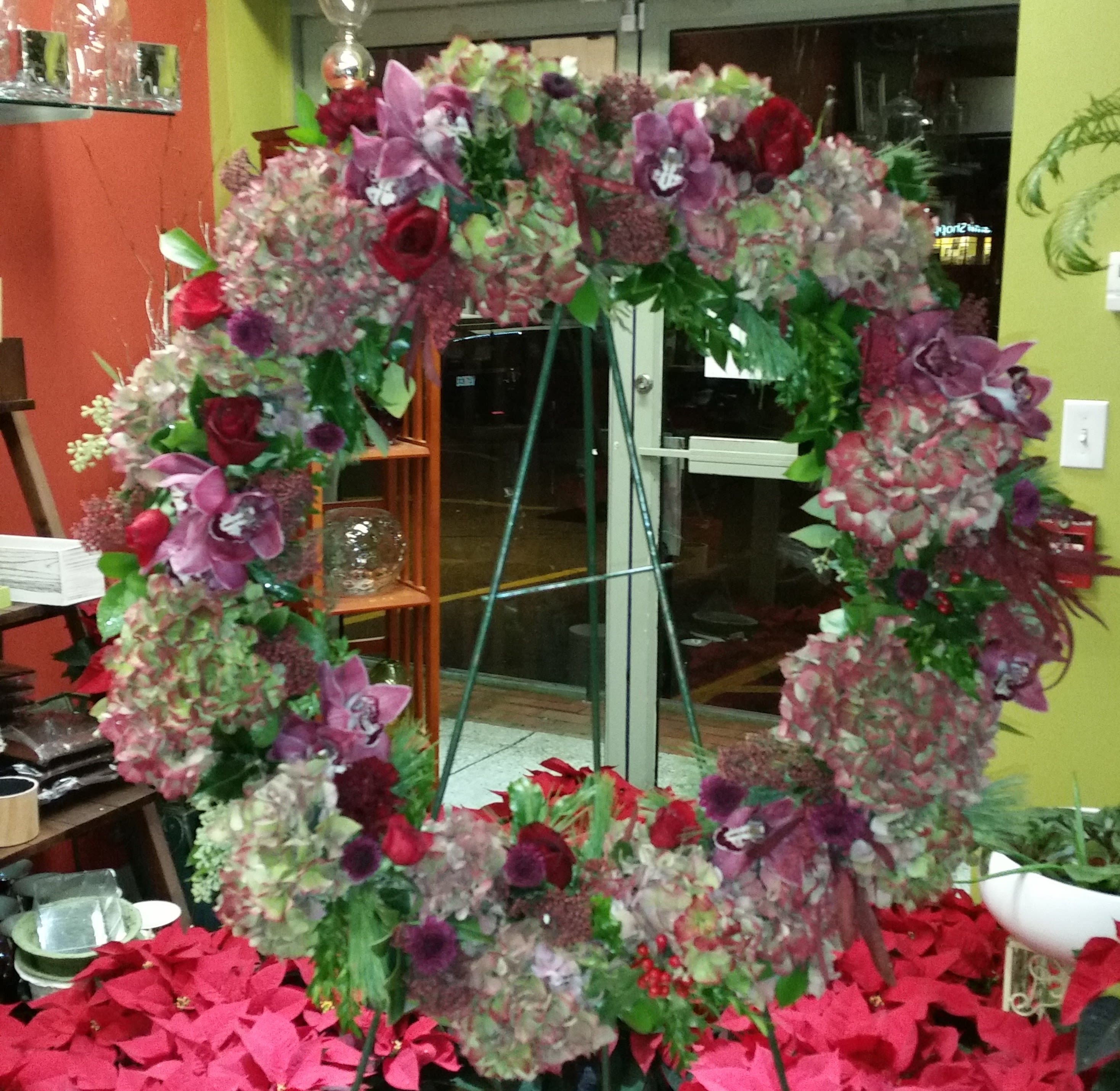 Large floral wreath with pink, purple, and red blooms on a stand