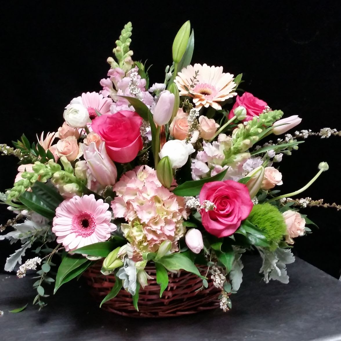 Penny's Pink Posies - This elegant grapevine basket is brimming with the prettiest pink cut flowers.  For a special birthday or any celebration, this lovely arrangement will be sure to be well-received.  Pink and white snapdragons, hydrangea and premium long-stemmed roses with so many tiny textural details, make this garden grouping a popular new edition!  We will be happy to add peonies once peony season takes hold in a few weeks! Just ask in special instructions below.