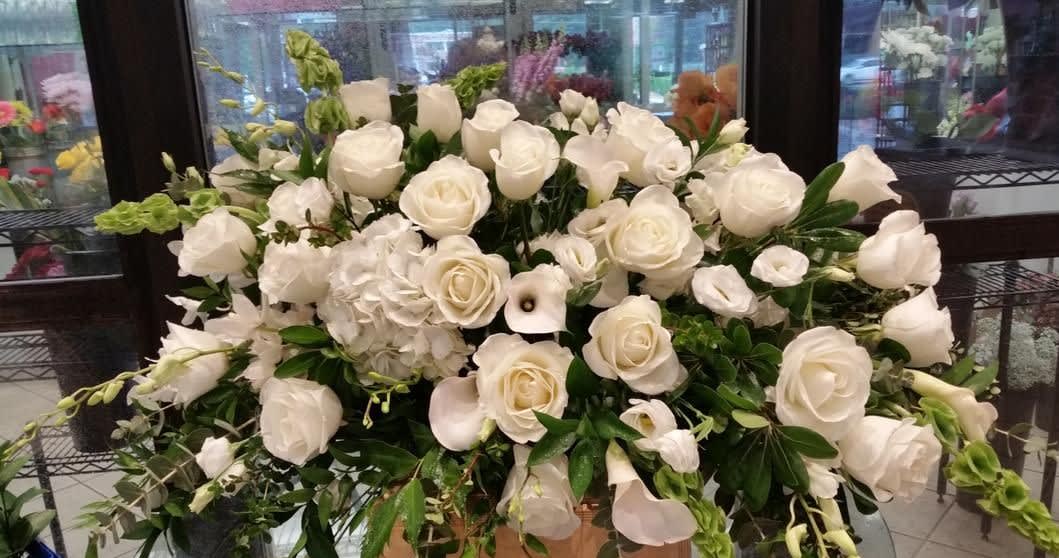 Large white rose arrangement with calla lilies and greenery