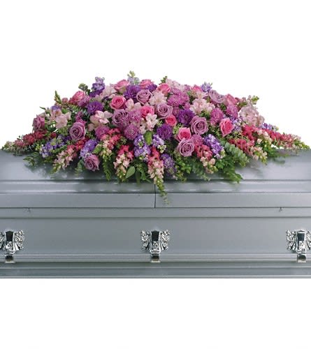 Pink and purple floral casket spray on a gray casket