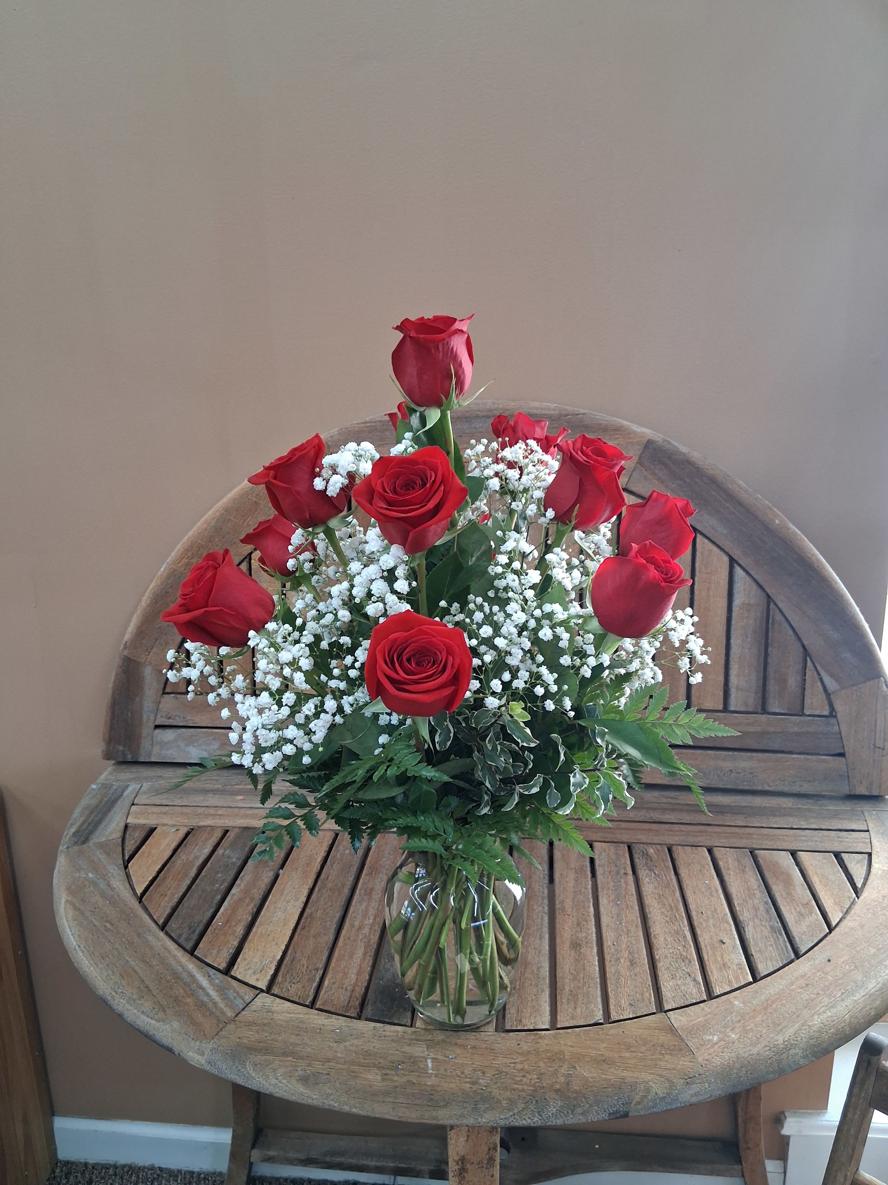 Red roses arranged in a clear glass vase with white baby's breath