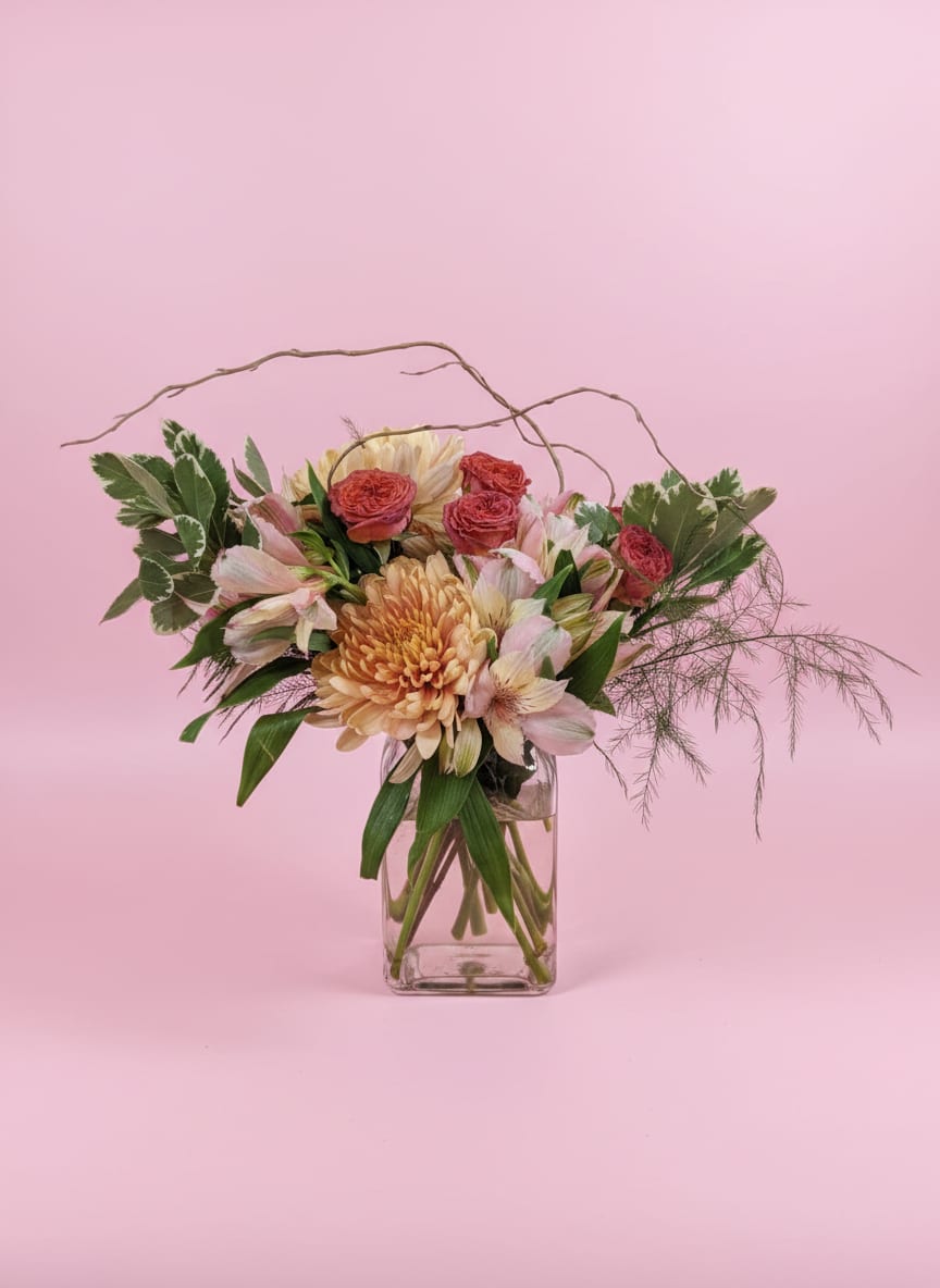 Mixed pink and peach flowers in a clear glass vase