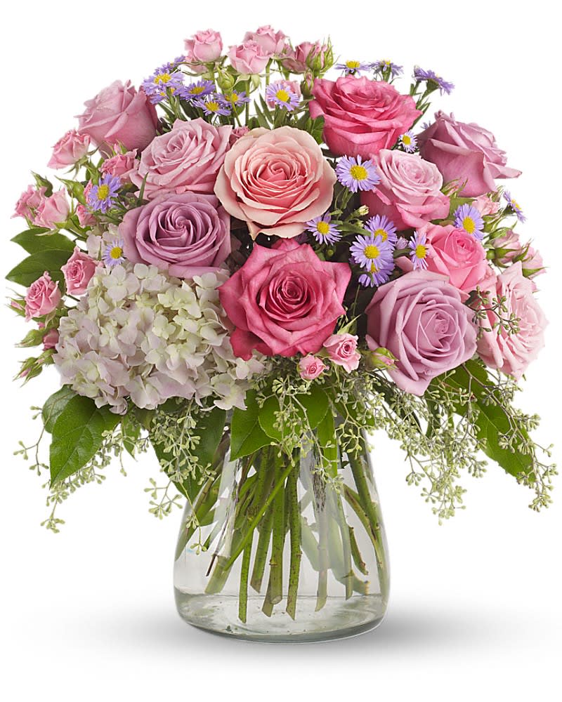 Bouquet of pink and lavender roses with small purple daisies in a glass vase
