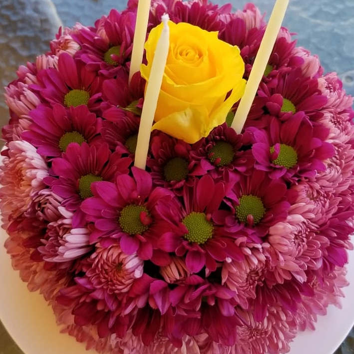 Round bouquet of pink daisies with a yellow rose in the center