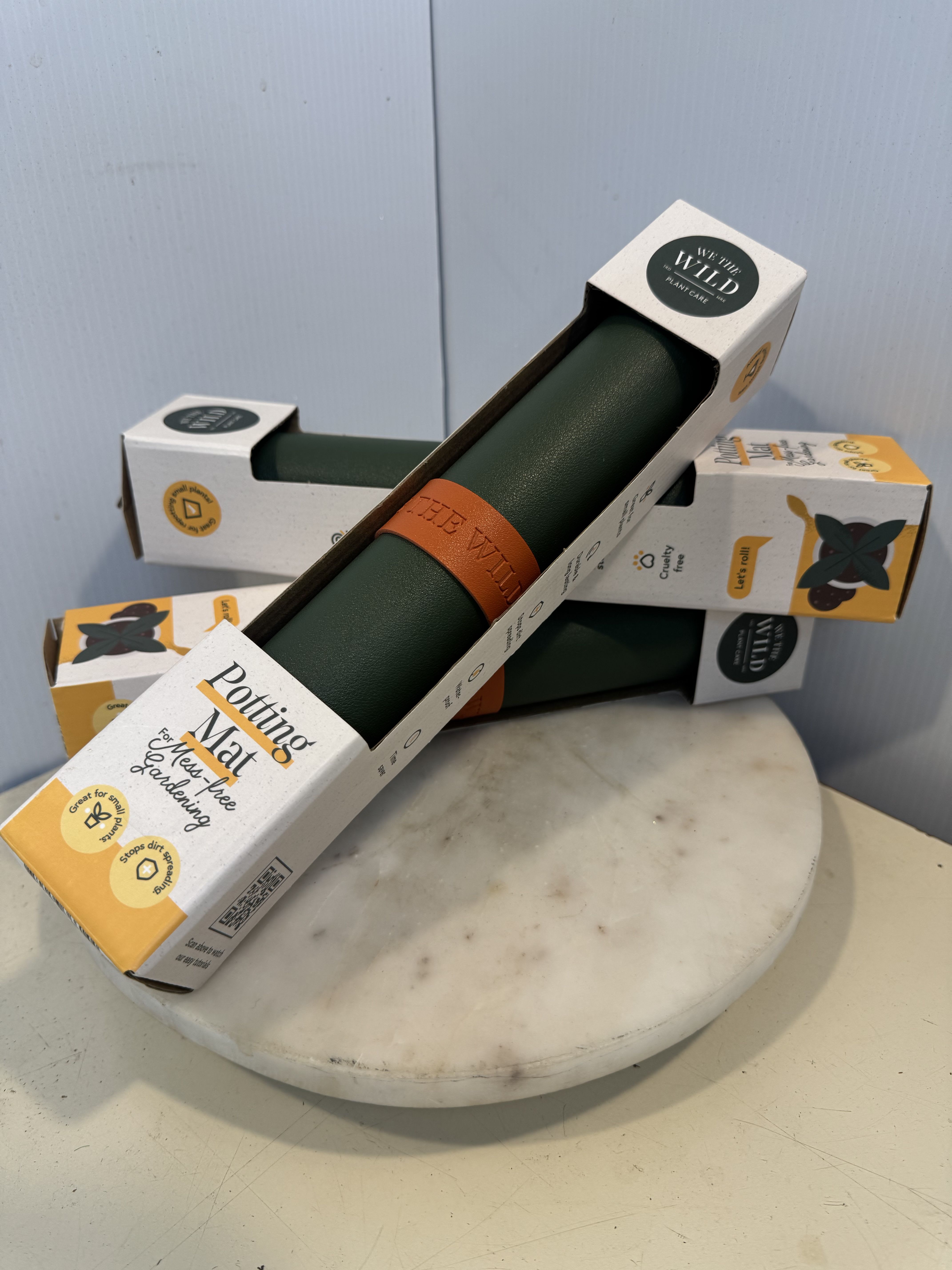 Stacked plant care mats in retail packaging on a round marble stand