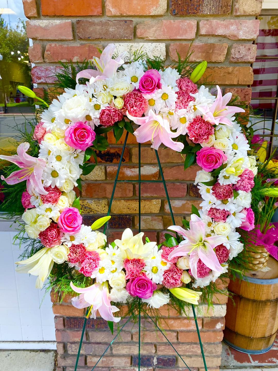 Large floral wreath with pink roses, white daisies, and lilies on an easel