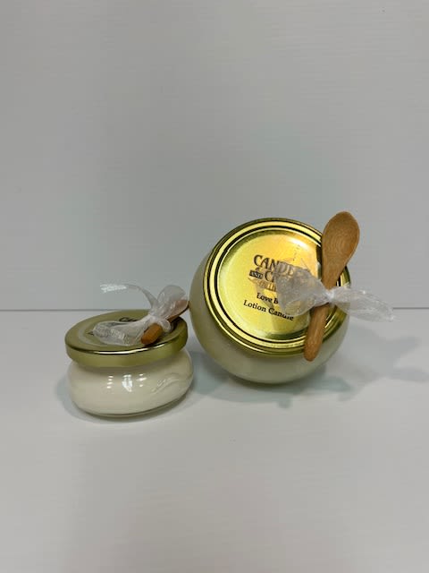 Two small candle jars with gold lids and wooden spoons tied on top